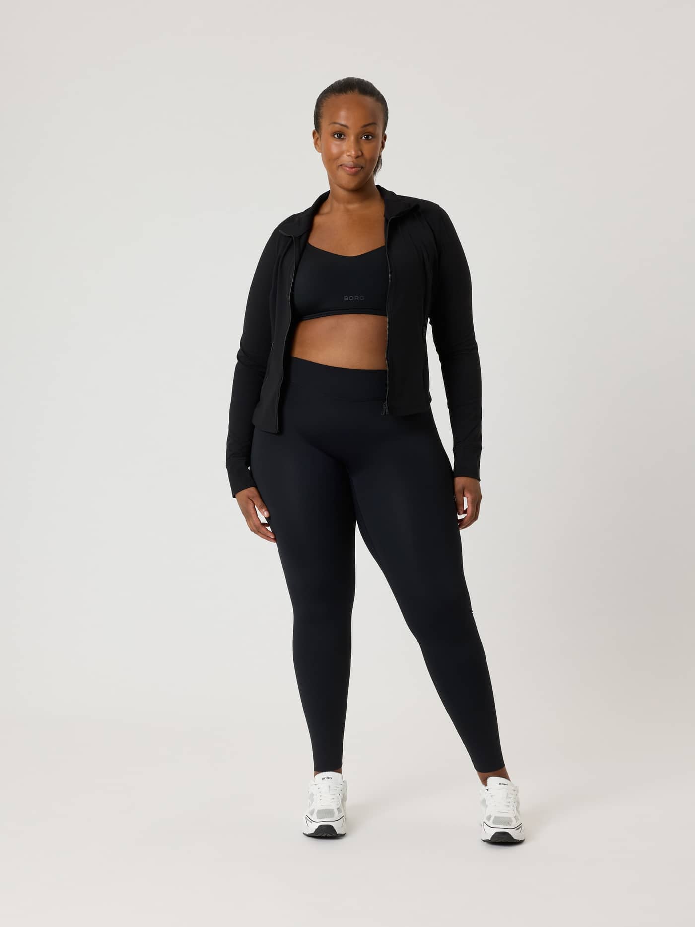 Full-body front view of a model wearing the slim-fit Alice Stenlöf Soft Zip Midlayer in Black Beauty (Black) for training. - Image 7