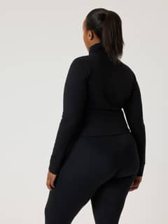 Back view of a model wearing the slim-fit Alice Stenlöf Soft Zip Midlayer in Black Beauty (Black) for training. - Image 6