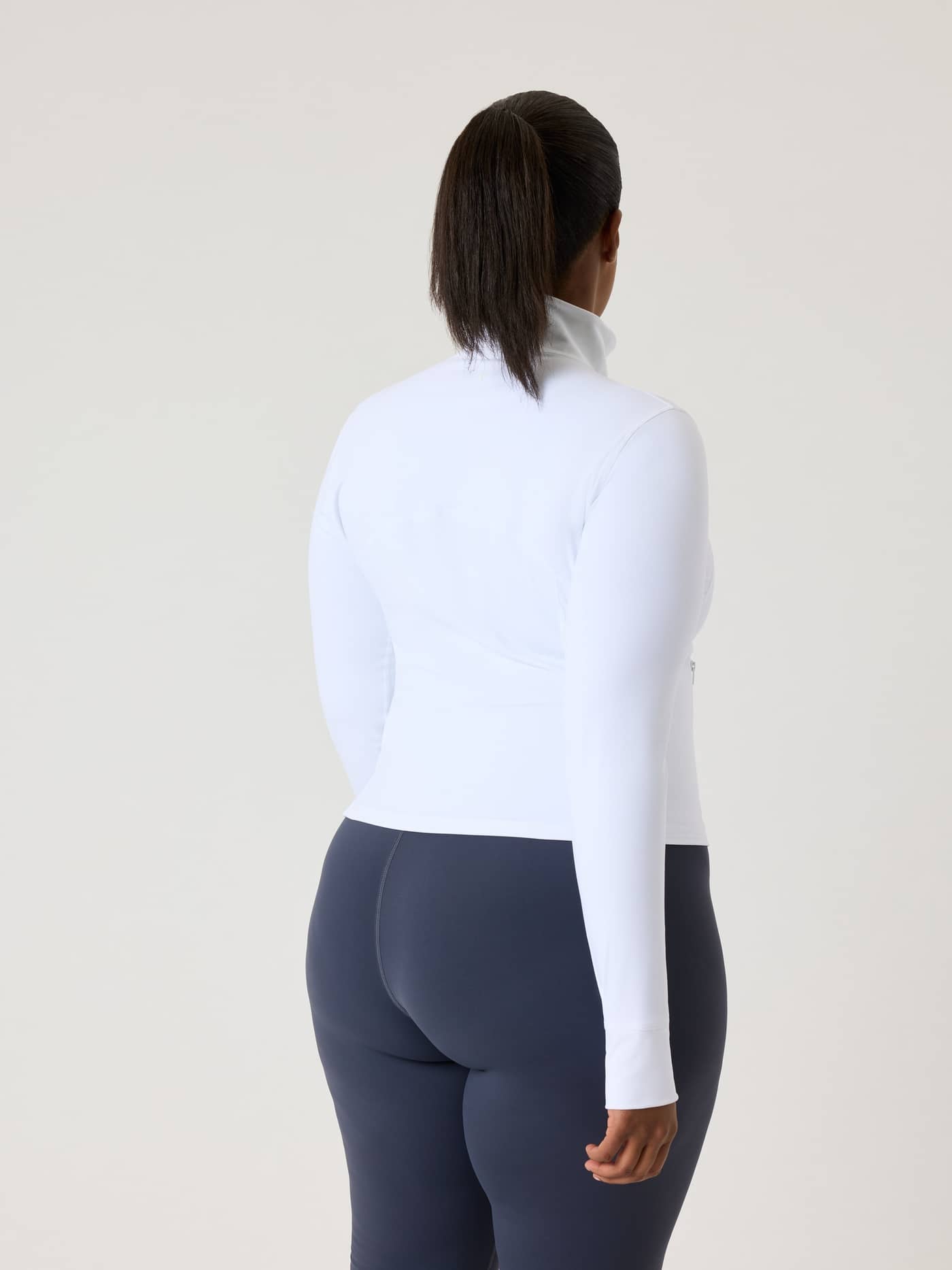 Back view of a model wearing the slim-fit Alice Stenlöf Soft Zip Midlayer in Brilliant White (White) for training. - Image 12