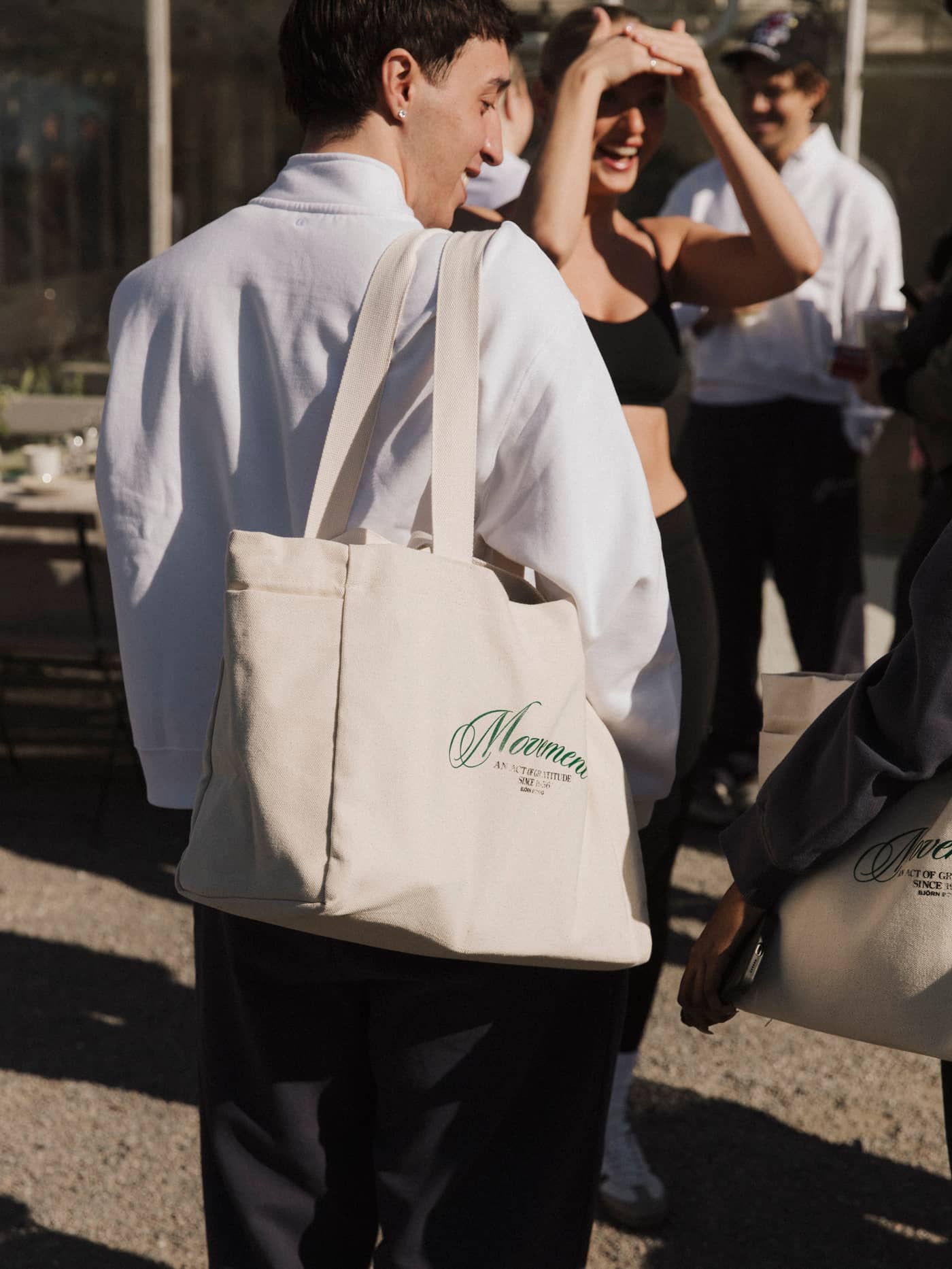 Alice Stenlöf Canvas Tote 24L in Egret (white) carried by a man, featuring durable cotton canvas and green graphic print. - Image 5