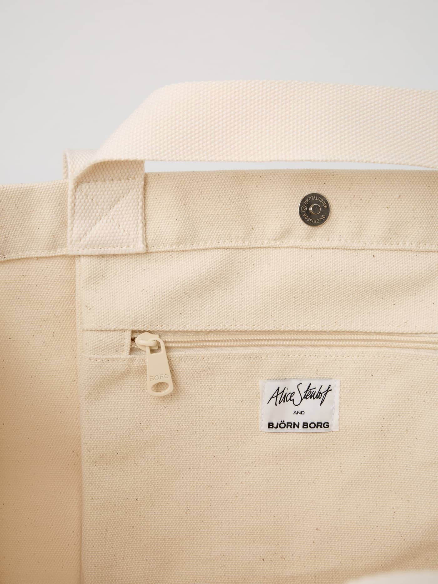 Interior view of the Alice Stenlöf Canvas Tote 24L in Egret (White), featuring a zip pocket and black logo label. - Image 6