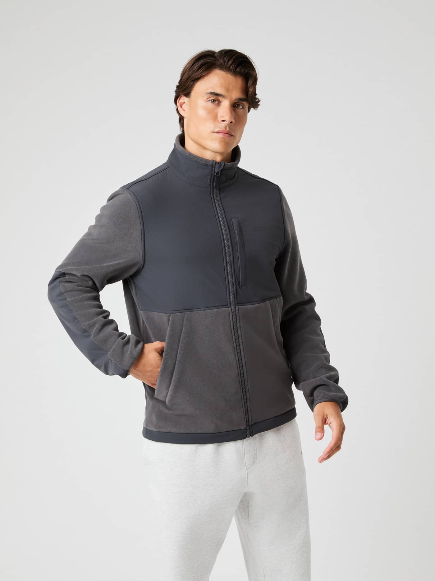 Front view of a man wearing the functional Borg Fleece Hybrid Jacket in Asphalt (Grey) for a stylish, athletic fit. - Image 2
