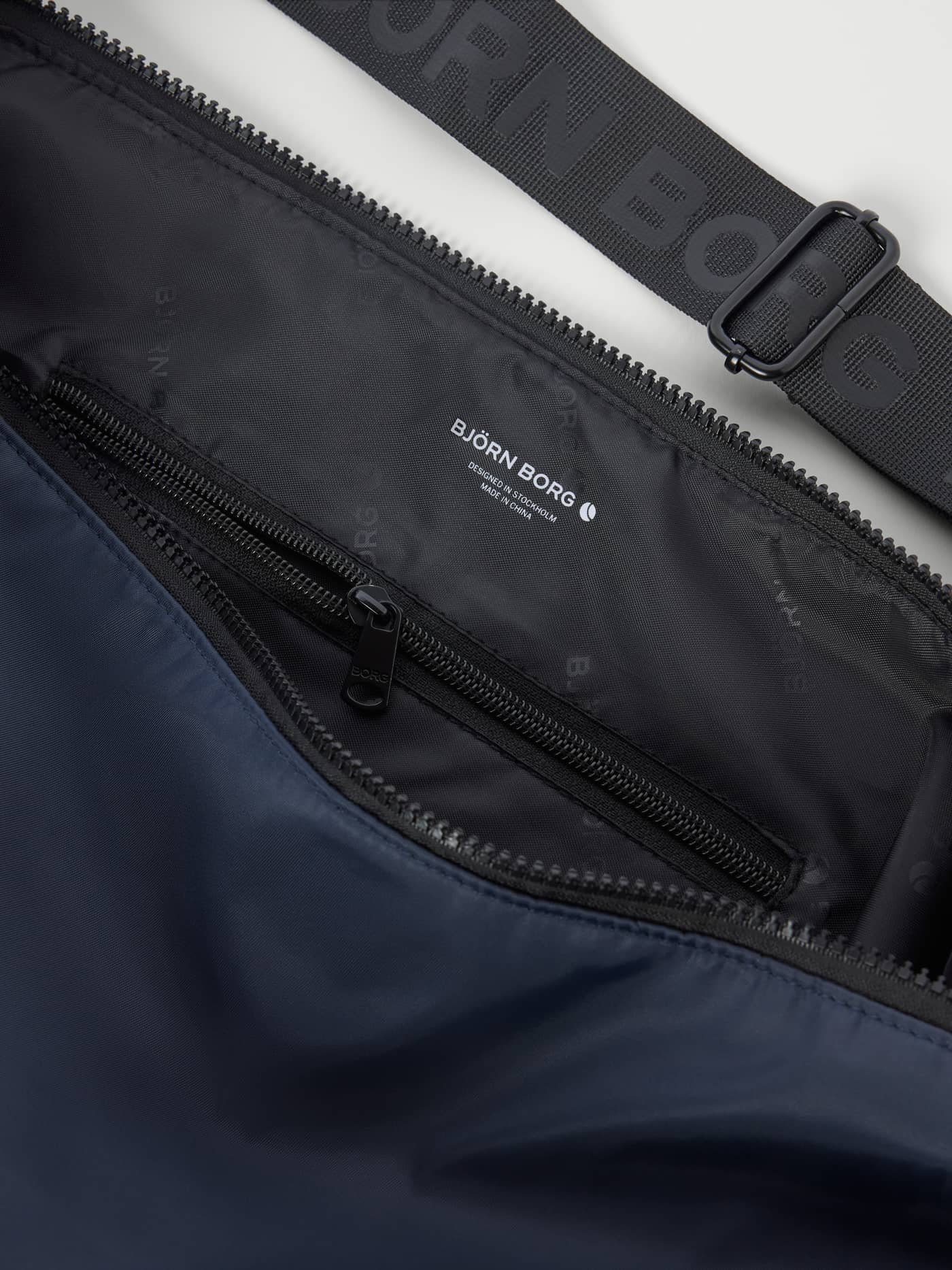 Borg Classic Shoulder Bag 13L i Odyssey Gray (Blå) til træning i genanvendt polyester med hvidt logo set tæt på. - Image 3