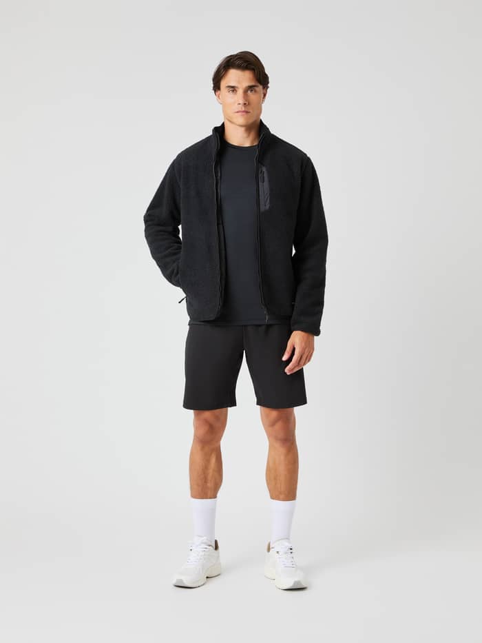 Full-body front view of a man wearing the Björn Borg Centre Pile Jacket in Black Beauty (Black) with black shorts. - Image 3