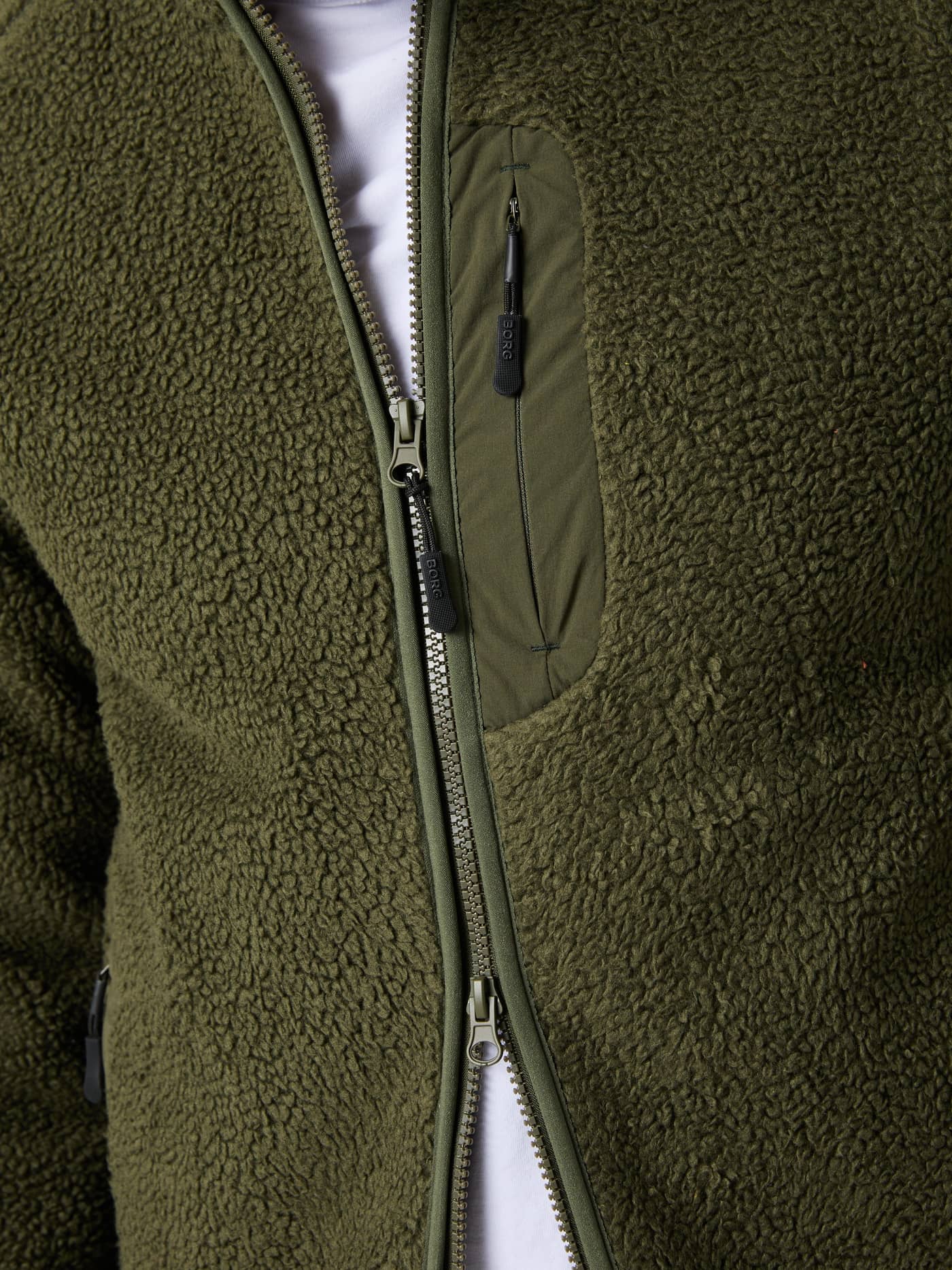 Close-up van het Björn Borg Centre Pile Jacket voor heren in Forest Night (Groen) met ritszak en zwarte logotrekkers. - Image 4