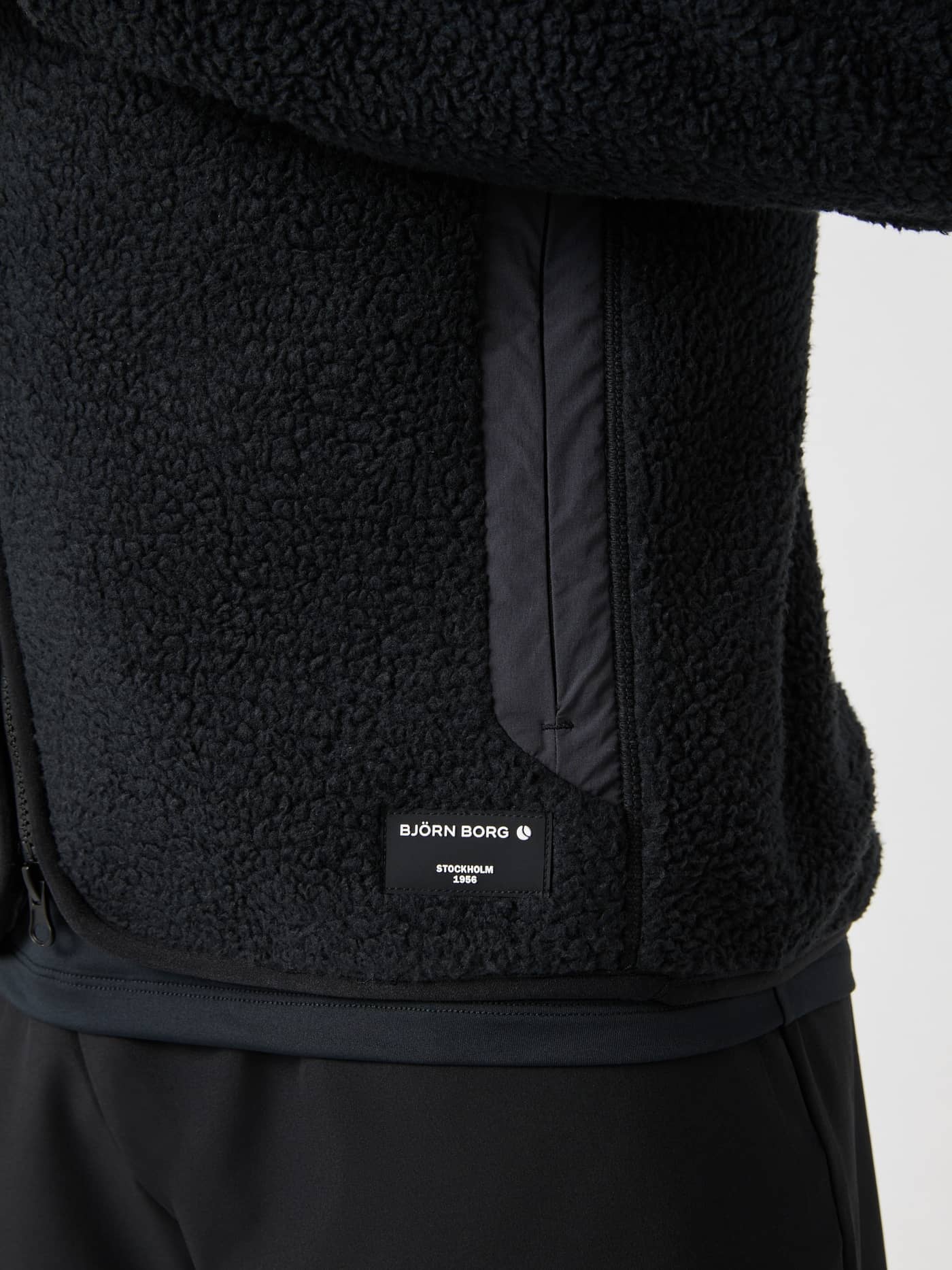 Gedetailleerd zijaanzicht van de Björn Borg Centre Pile Jacket in Black Beauty (Zwart) met wit logo en pile-textuur. - Image 5