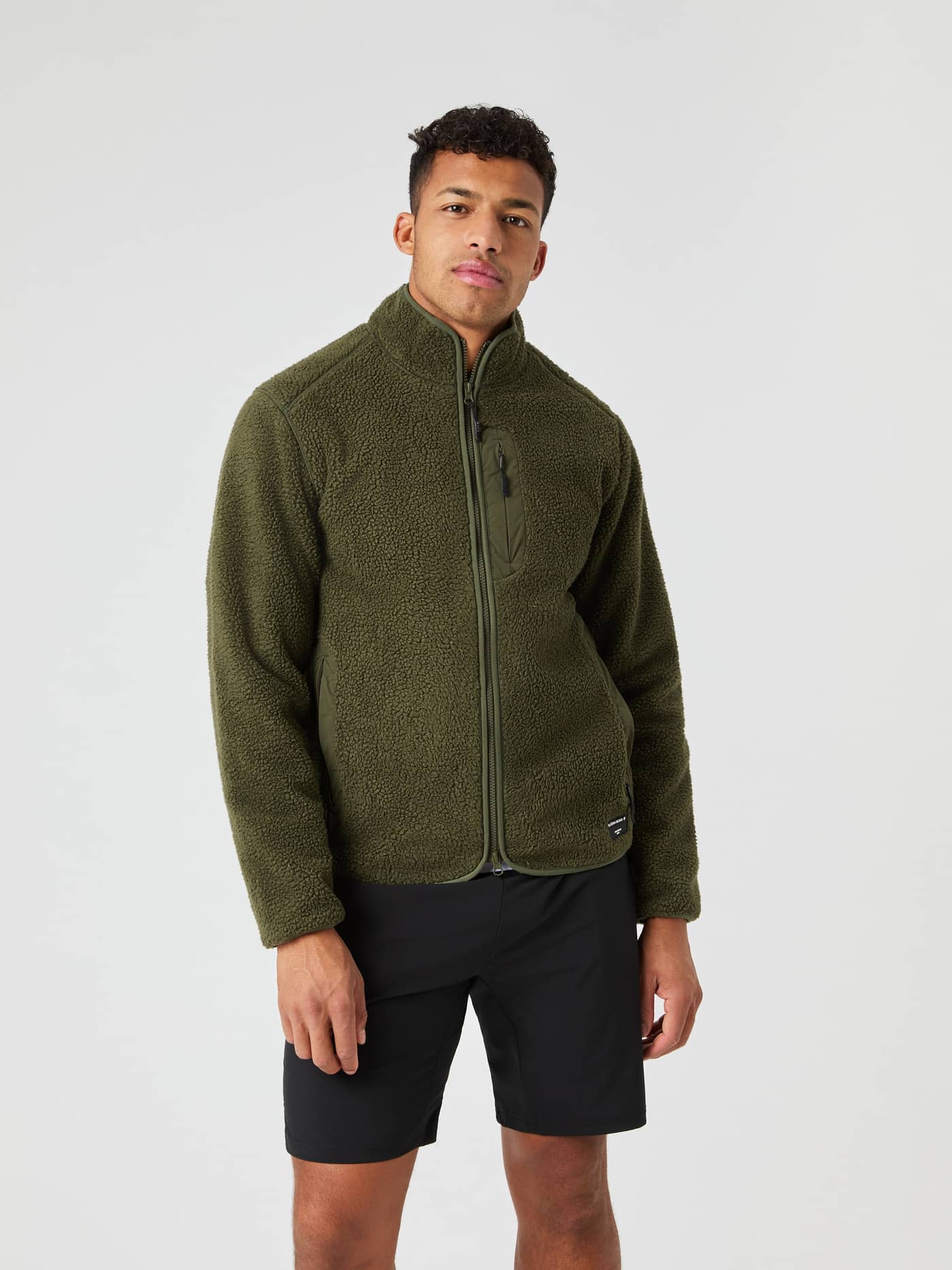 Front view of a man in the Björn Borg Centre Pile Jacket in Forest Night (Green) with a black logo and functional pile. - Image 1