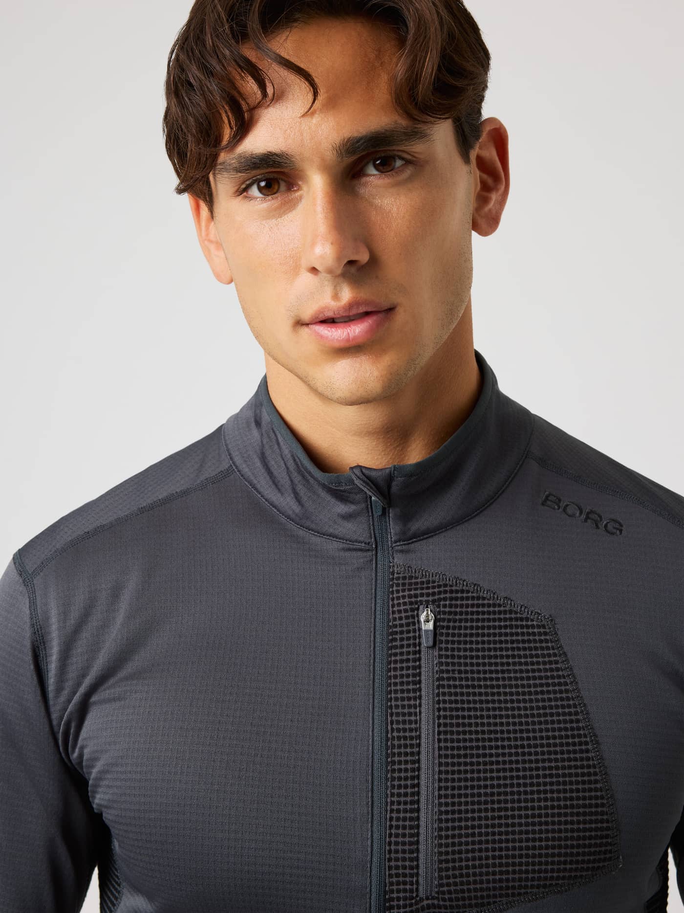 Close-up of a man wearing the Borg Fleece Midlayer in Asphalt (Black), a waffle fleece training top with a half-zip. - Image 1