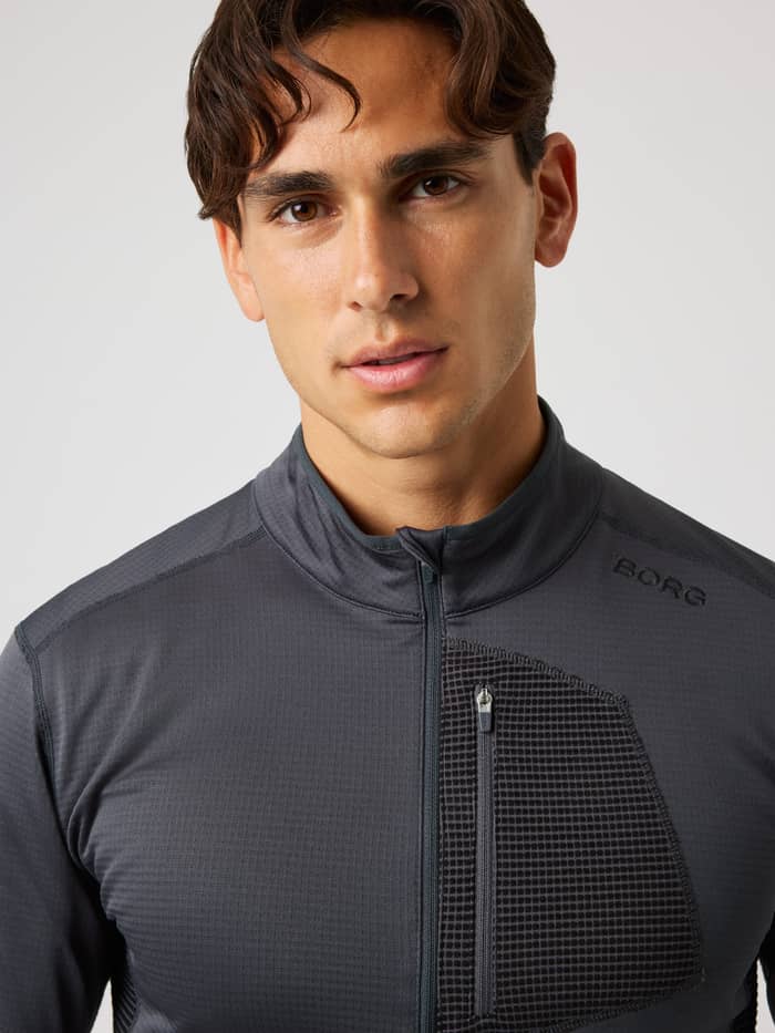 Close-up of a man wearing the Borg Fleece Midlayer in Asphalt (Black), a waffle fleece training top with a half-zip.