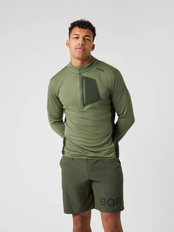 Vista frontal de un hombre con la Borg Fleece Midlayer en Forest Night (Verde), logo negro y ajuste de entrenamiento.