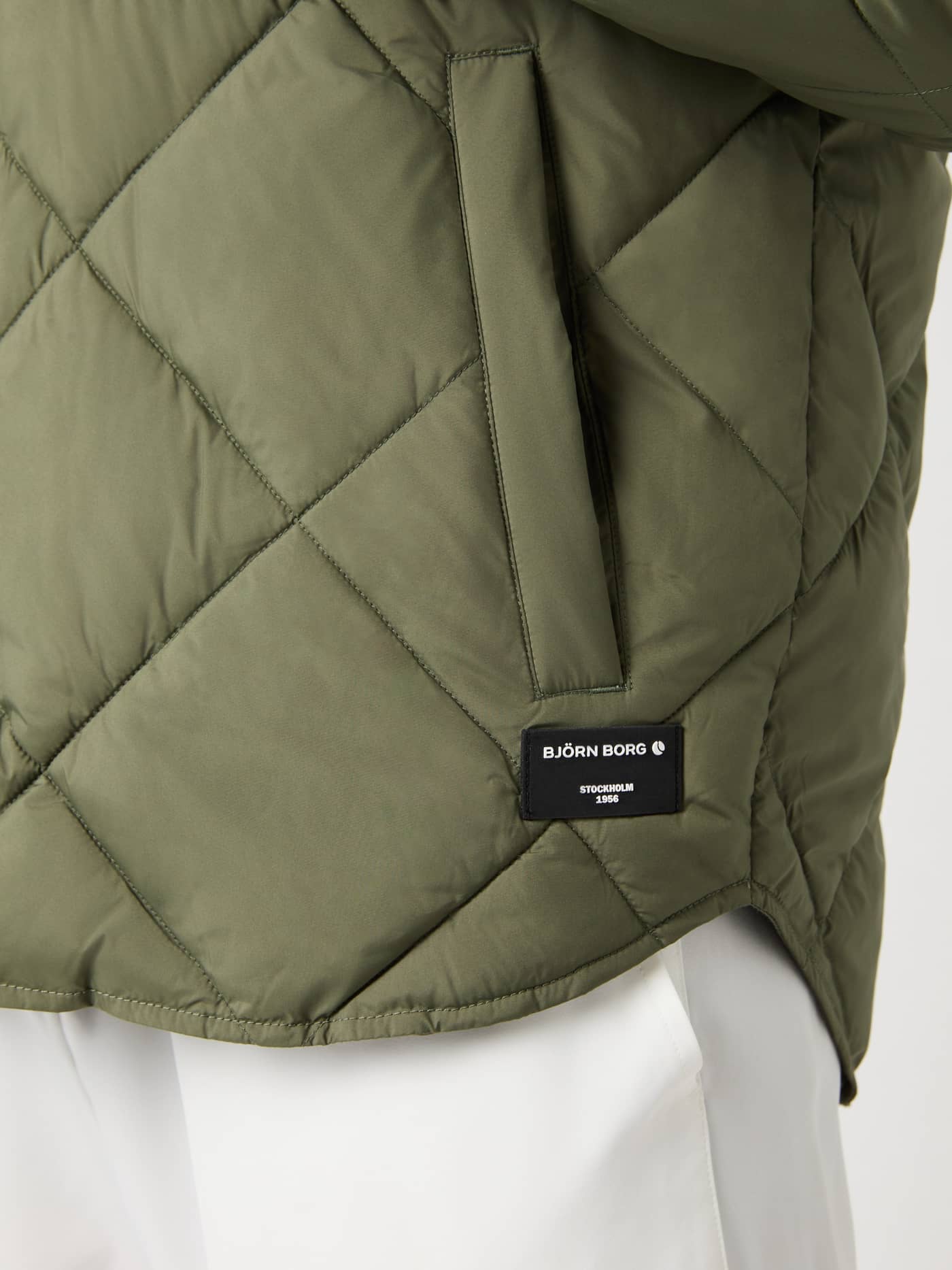 Nahaufnahme des Centre Quilted Overshirt in Dusty Olive (Grün) mit Rautensteppung und schwarzem Logo-Patch. - Image 6