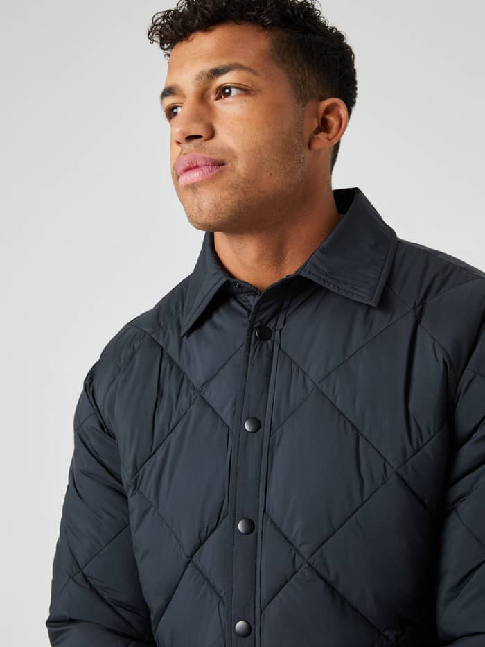 Front view of a man wearing the functional Centre Quilted Overshirt in Black Beauty (Black) with a performance padded design. - Image 4