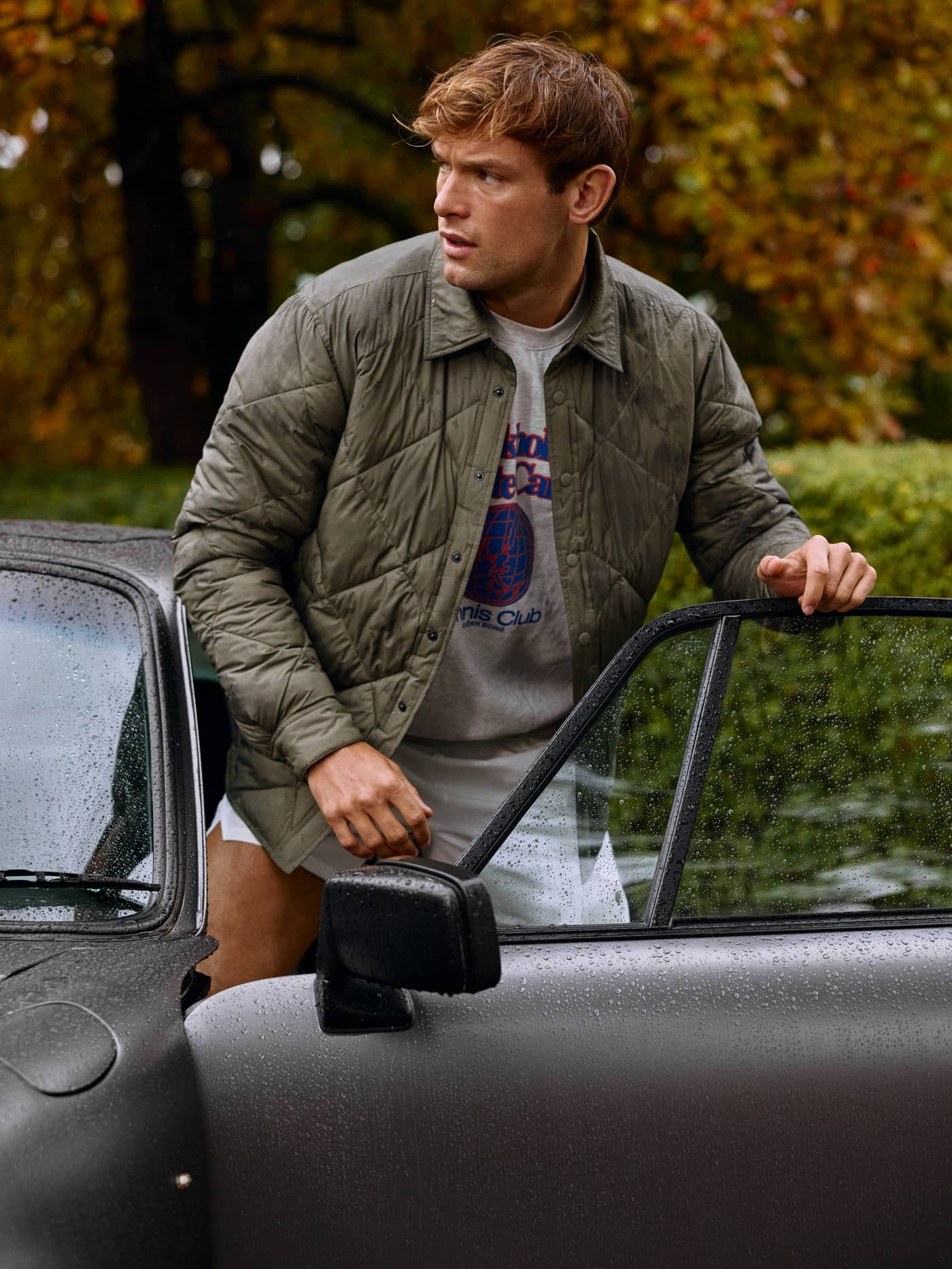 Mann im Björn Borg Centre Quilted Overshirt in Dusty Olive (Grün) am Auto zeigt Stil und funktionale Performance. - Image 1
