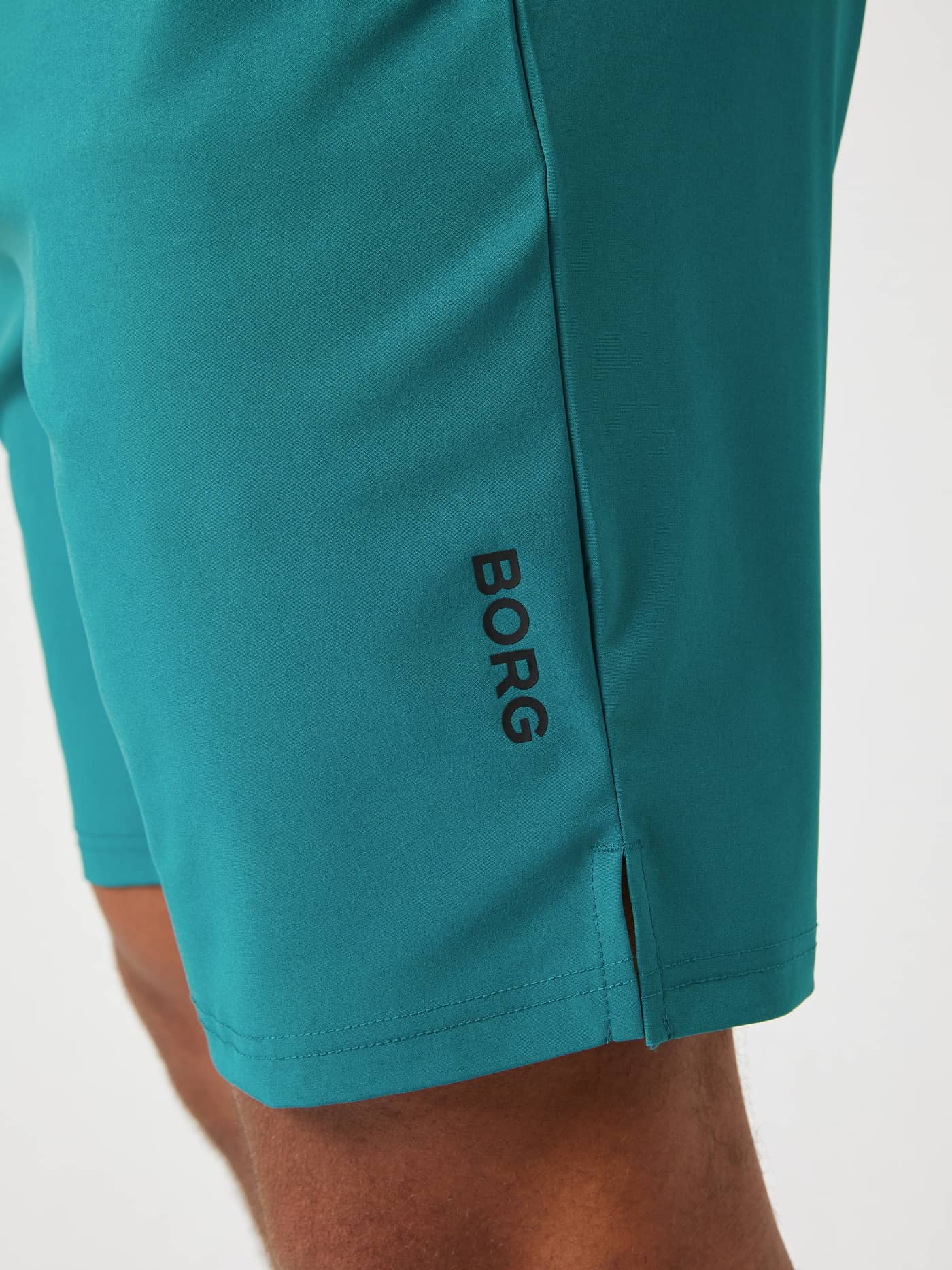 Gros plan du Borg Athletic 9 Inch Shorts en Shaded Spruce (Bleu) avec logo noir et fente latérale pour l'entraînement. - Image 4