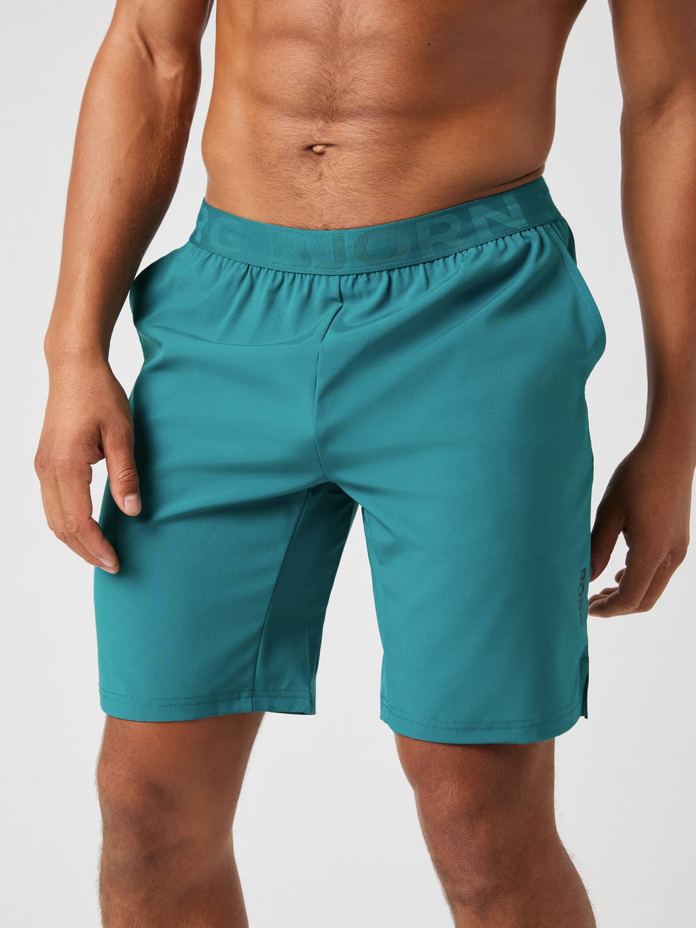 Vue de face d'un homme en Borg Athletic 9 Inch Shorts Shaded Spruce (Bleu) avec taille logotée pour l'entraînement. - Image 2
