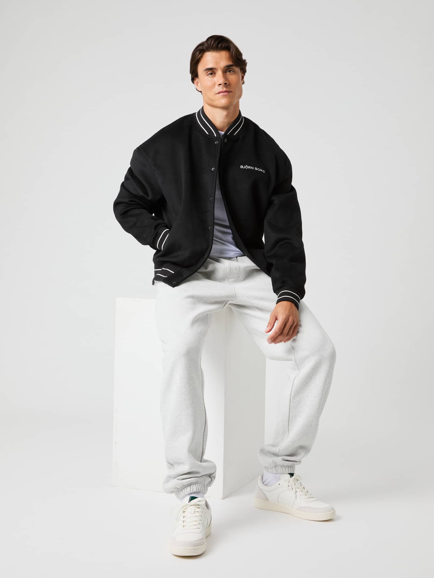 Sitzender Mann in der wattierten Borg Varsity Jacket aus Wollmischung in Black Beauty (Schwarz) mit weißem Logo. - Image 6