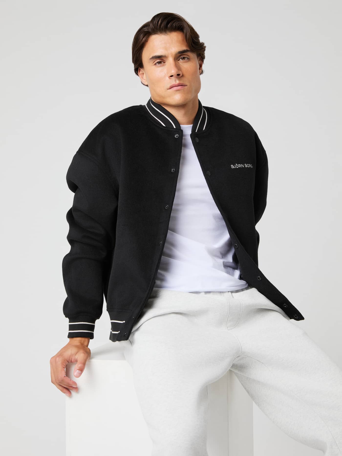 Vorderansicht eines Mannes in der Borg Varsity Jacket in Black Beauty (Schwarz) mit Varsity-Streifen und weißem Logo. - Image 1