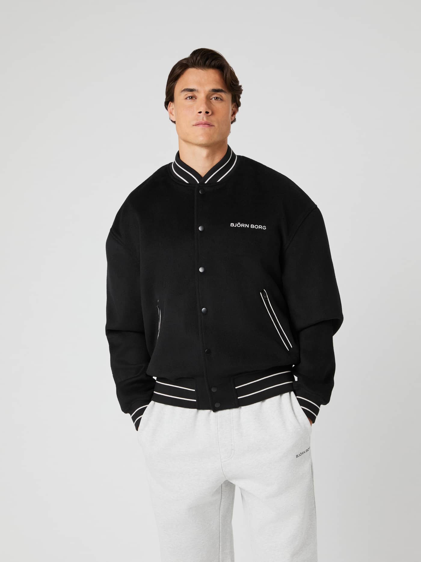 Vorderansicht eines Mannes in der Borg Varsity Jacket aus Wollmischung in Black Beauty (Schwarz) mit weißem Logo. - Image 3