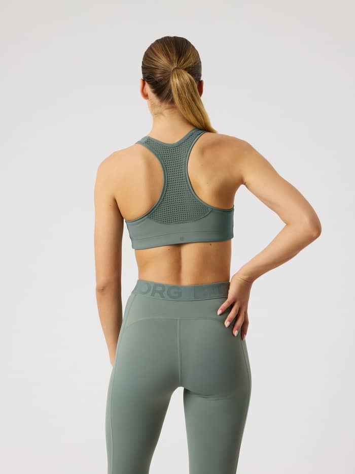 Back view of a model wearing the Borg Mid Support Sports Bra in green with a mesh racerback for a performance training fit. - Image 4