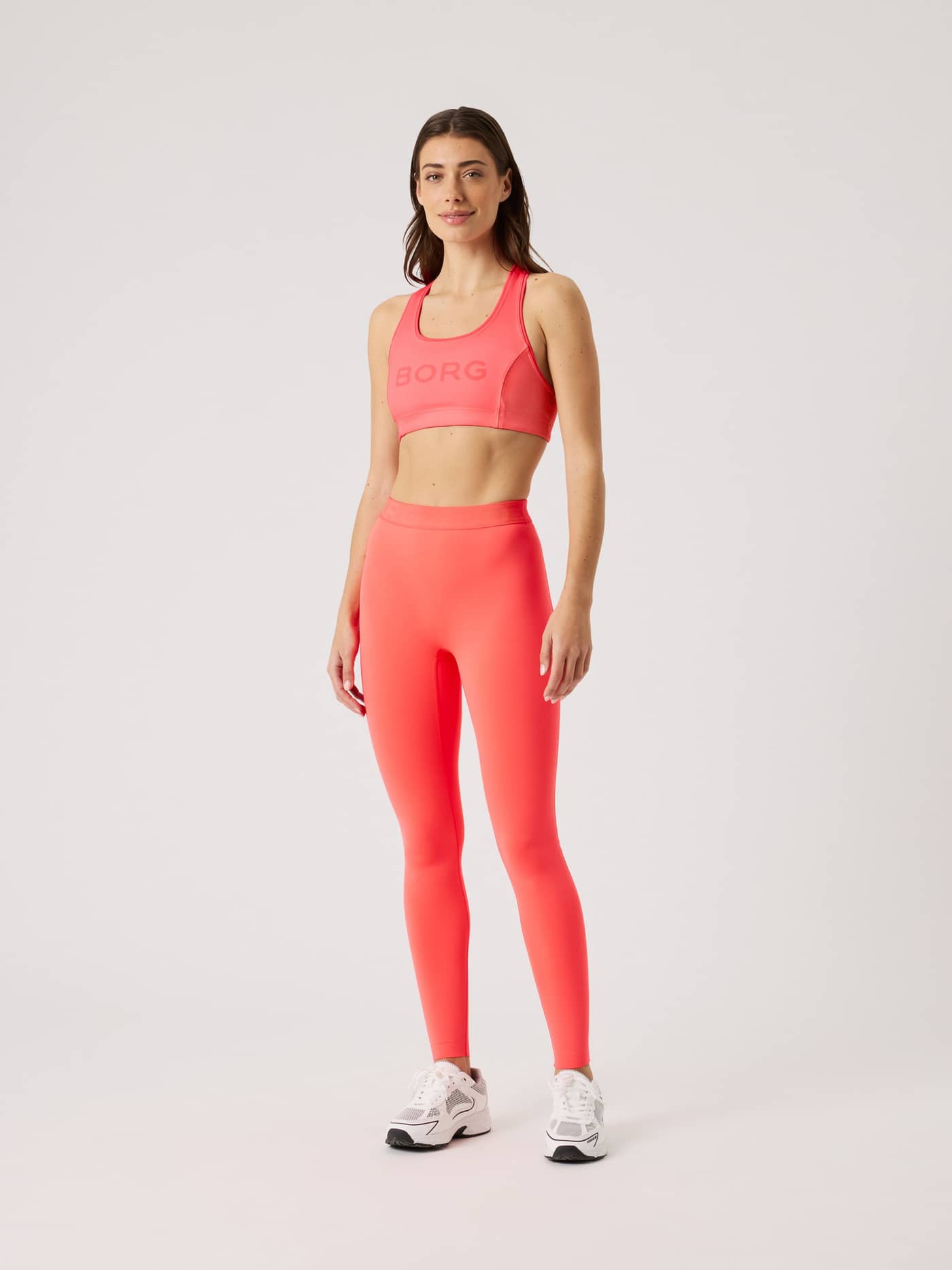Full-body front view of a woman in the pink Borg Mid Support Sports Bra with a pink logo, offering a stylish training fit. - Image 3
