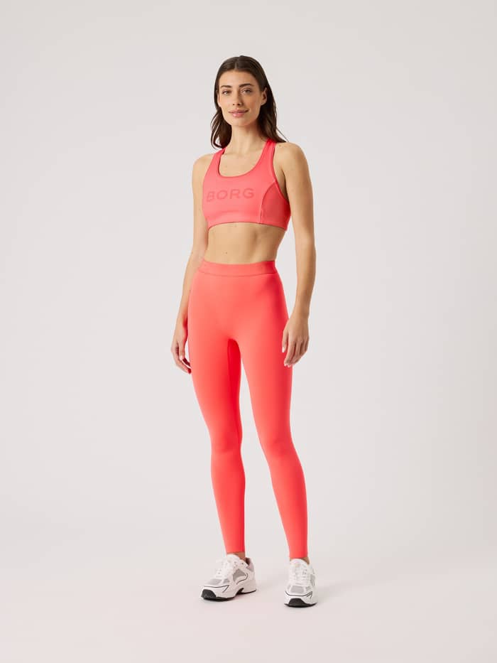 Full-body front view of a woman in the pink Borg Mid Support Sports Bra with a pink logo, offering a stylish training fit. - Image 3