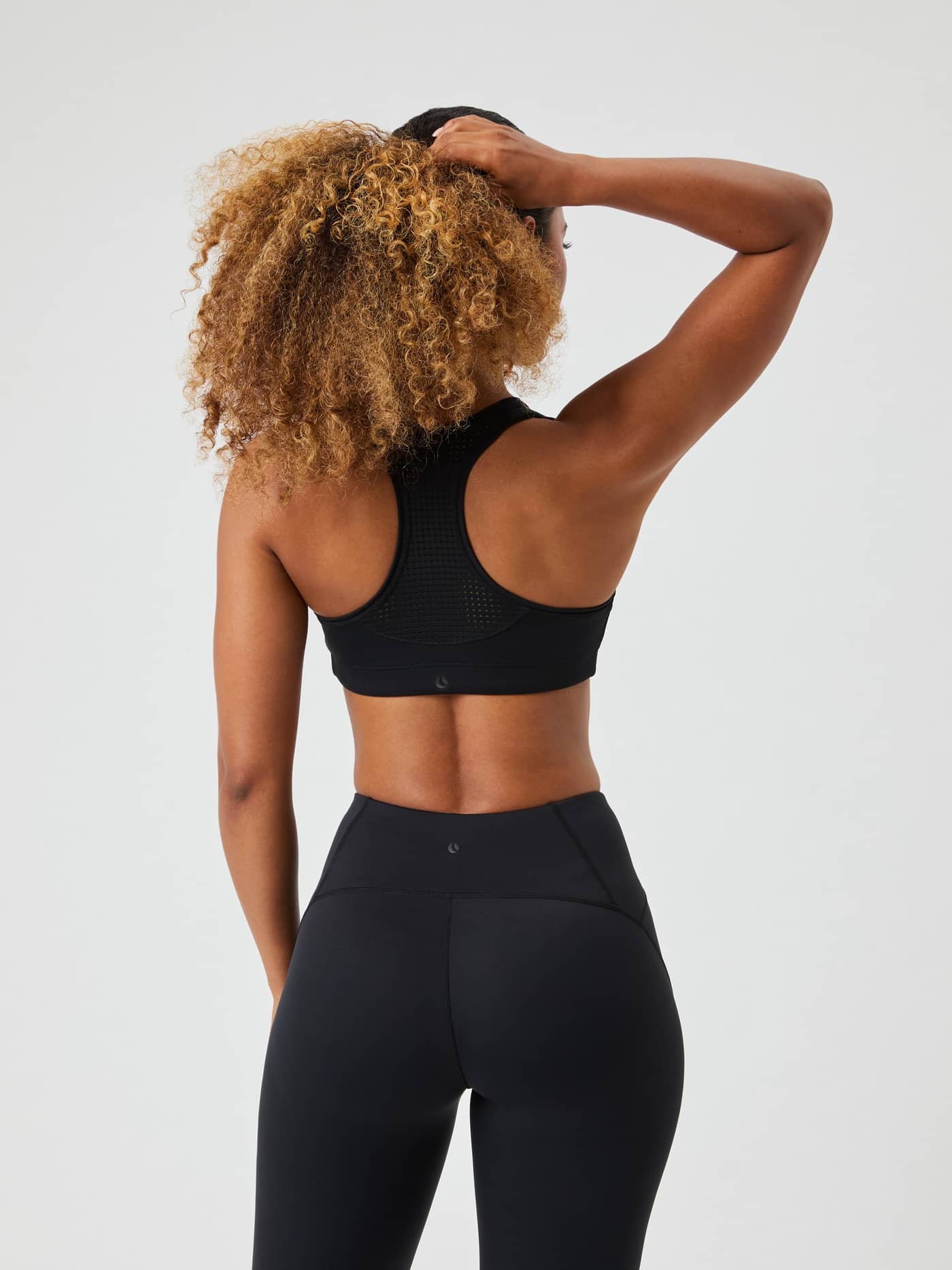 Back view of a model wearing the black Borg Mid Support Sports Bra, featuring a breathable mesh panel for a training fit. - Image 2