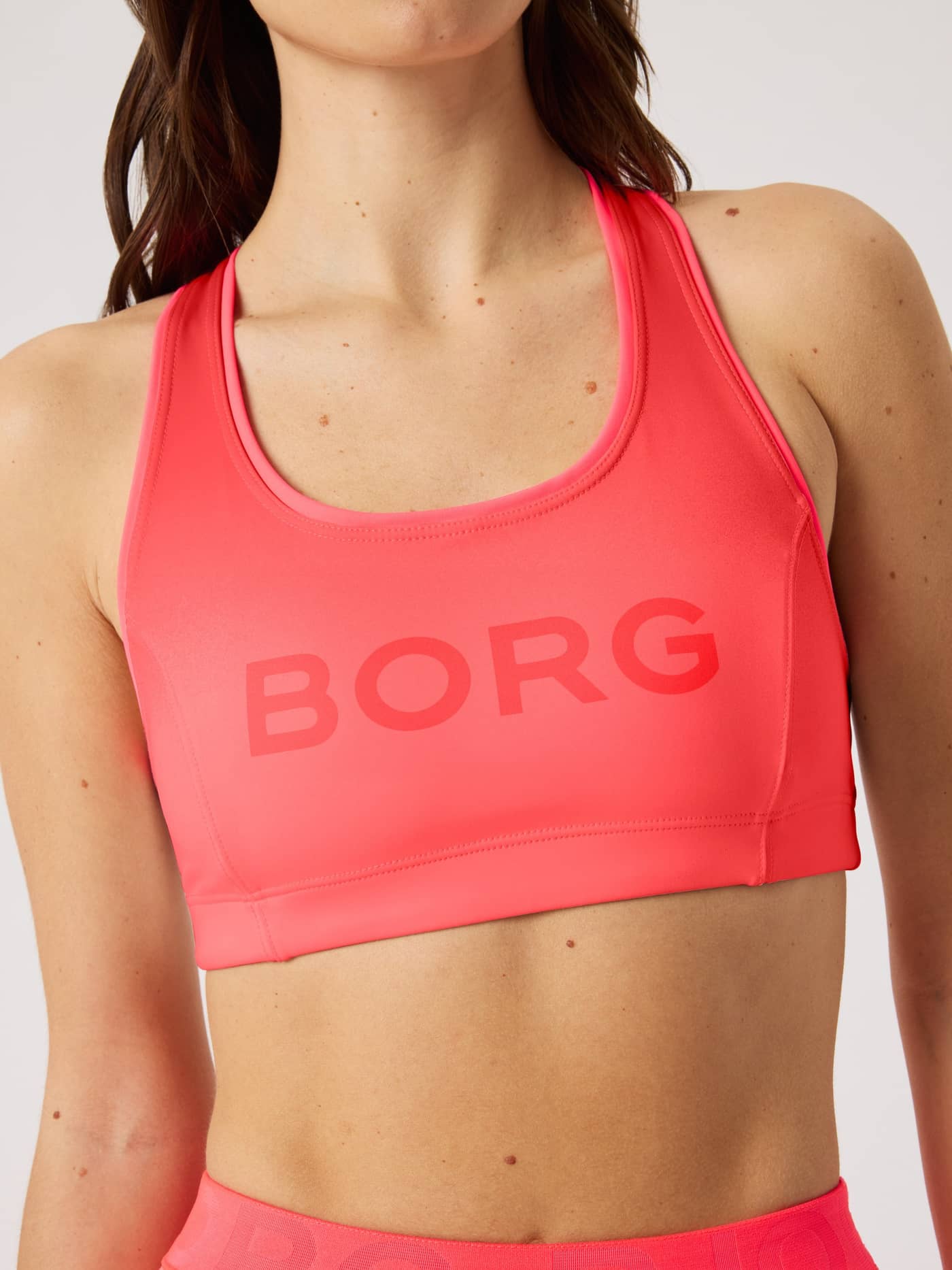 Front view of a model wearing the pink Borg Mid Support Sports Bra for training, with a tonal logo and supportive fit. - Image 5