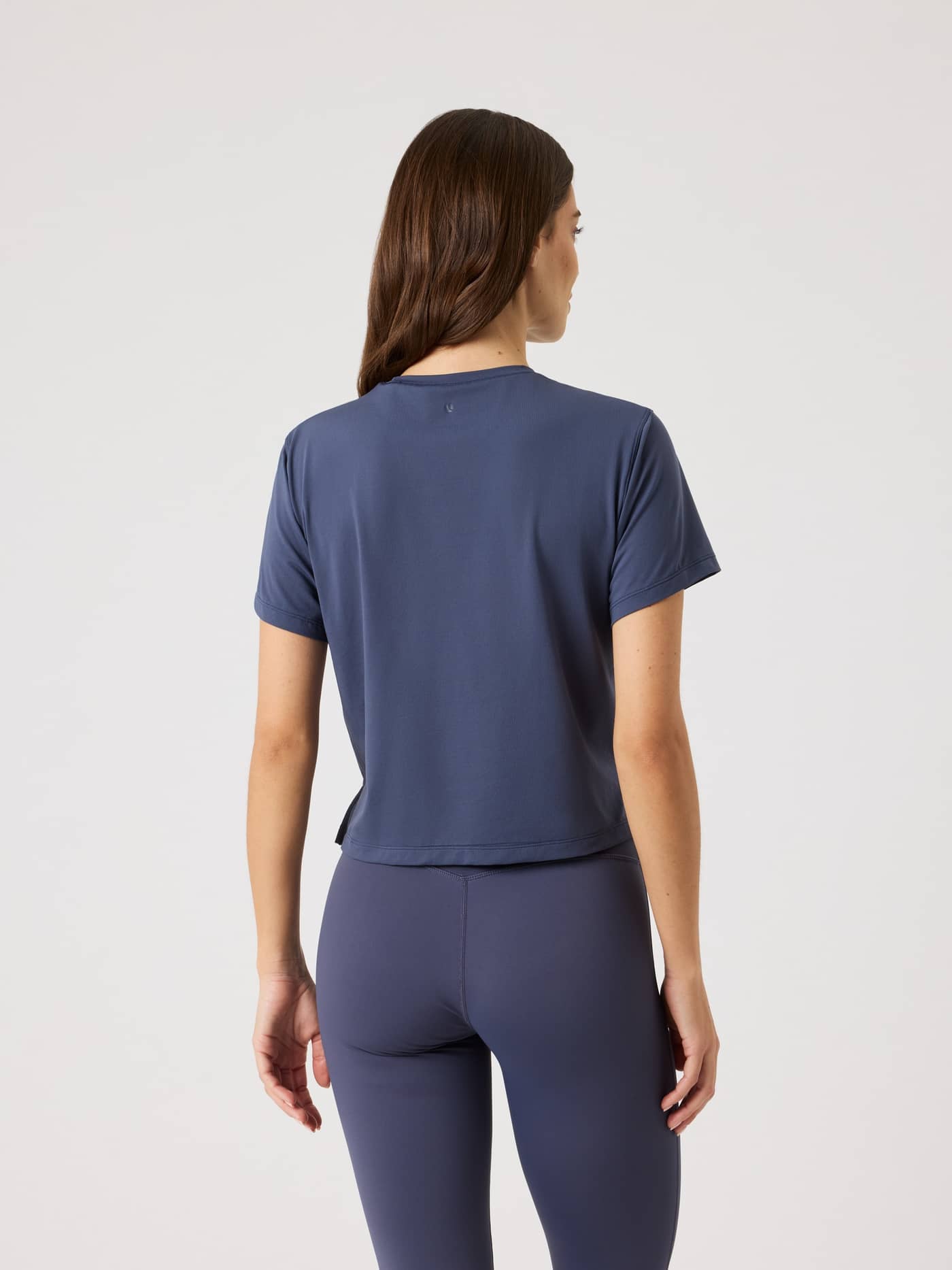 Back view of a woman wearing the Odyssey Gray (Navy) Borg Cropped T-Shirt, a breathable training top with a stylish fit. - Image 2