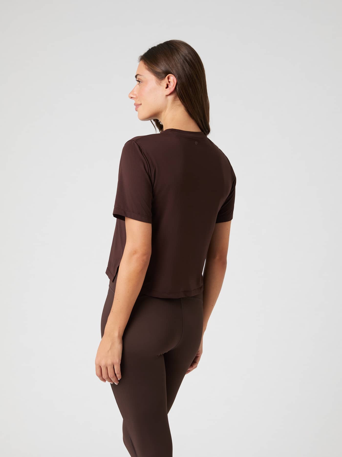 Back and side view of a model wearing the brown Borg Cropped T-Shirt, showcasing the fit and side slit. - Image 2