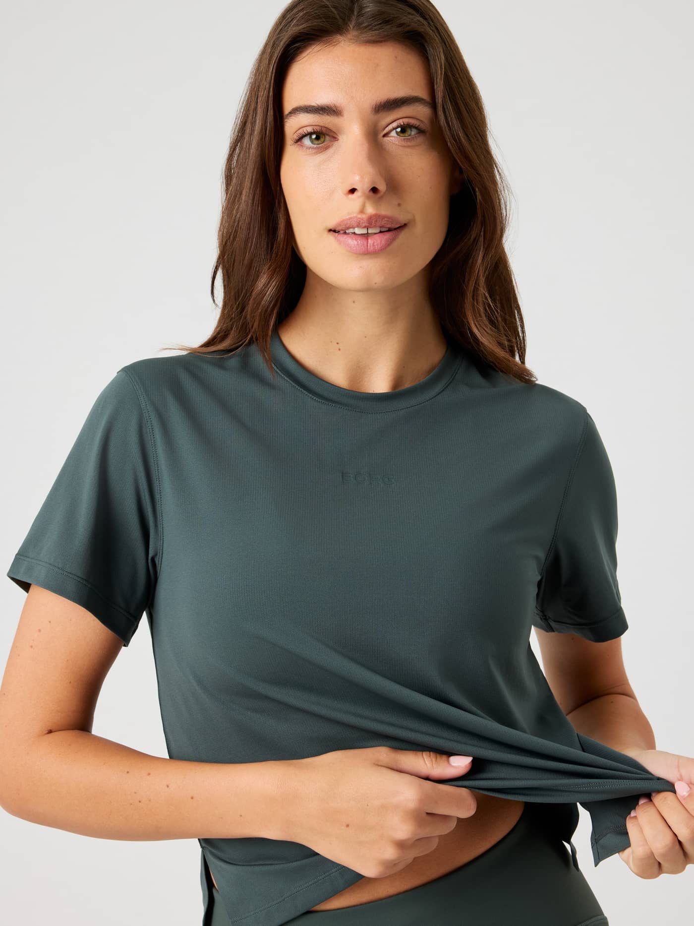 Front view of a woman in the Borg Cropped T-Shirt in Urban Chic (Green), a stylish training top with a tonal logo. - Image 4