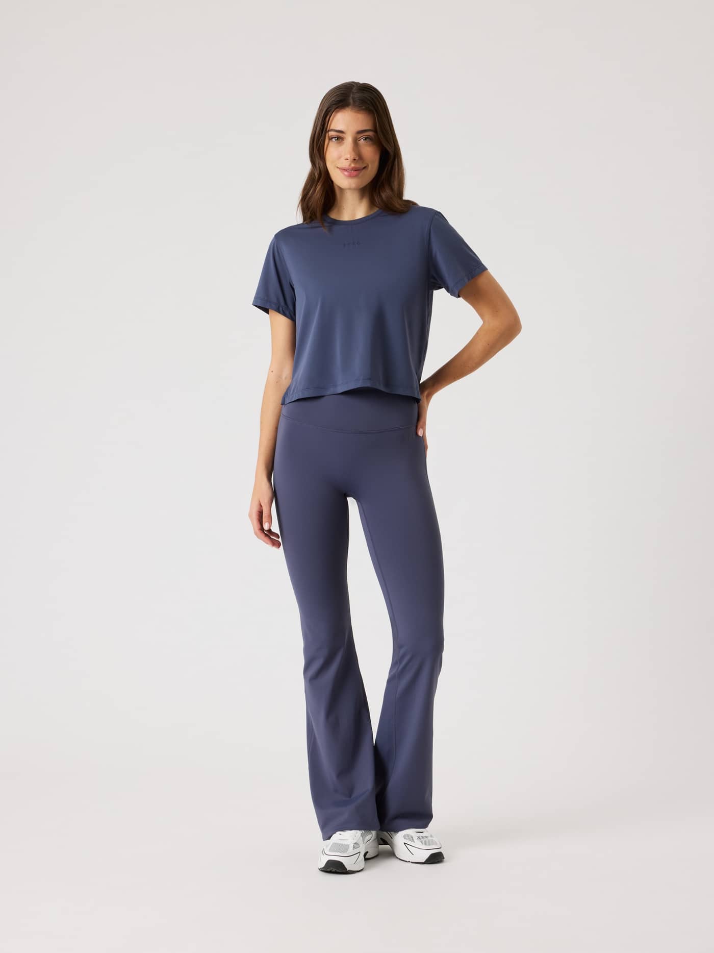 Full-body front view of a woman wearing the training Borg Cropped T-Shirt in Odyssey Gray (Navy) with matching leggings. - Image 3