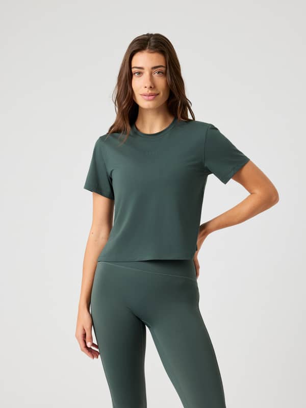 Front view of a model wearing the lightweight Borg Cropped T-Shirt in Urban Chic (Green) with matching training leggings.