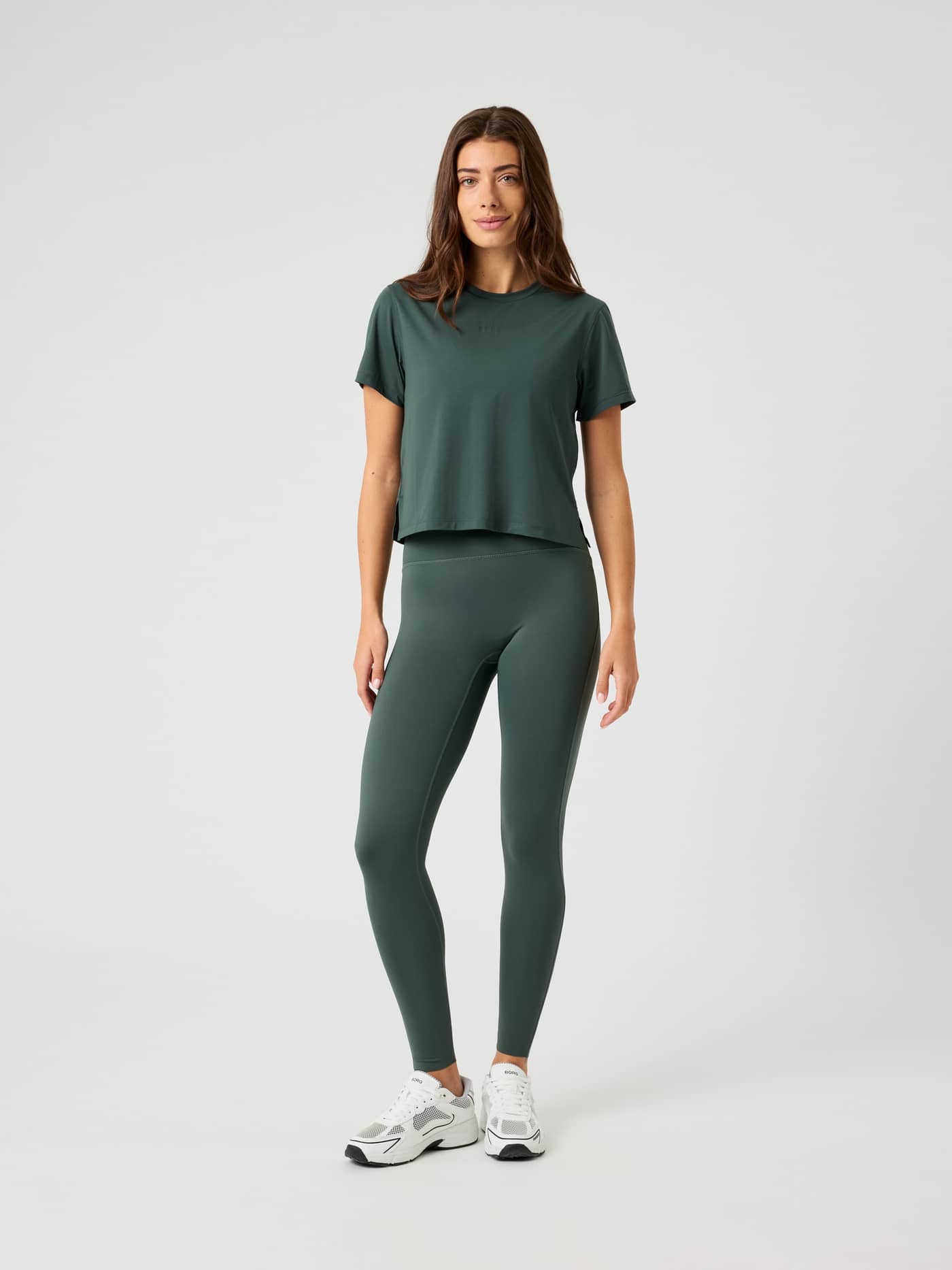 Full-body front view of a woman wearing the Borg Cropped T-Shirt in Urban Chic (Green) with matching training leggings. - Image 3
