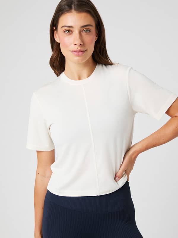 Front view of a model in the Studio Soft T-Shirt in Tofu (White), a soft modal training top with a flattering cropped fit.