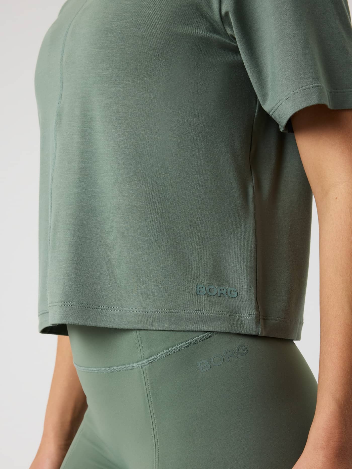 Close-up van het Studio Soft T-Shirt van modal in Agave Green (Groen) voor training met een ton-sur-ton logo en cropped fit. - Image 4