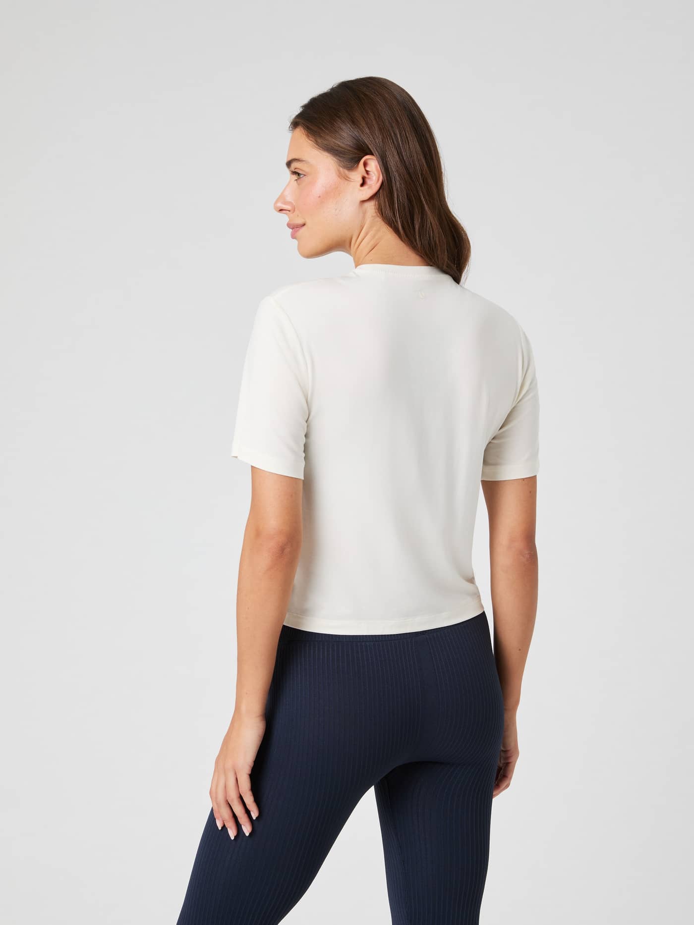 Back view of a woman wearing the Studio Soft T-Shirt in Tofu (White), a soft cropped modal top for training performance. - Image 2