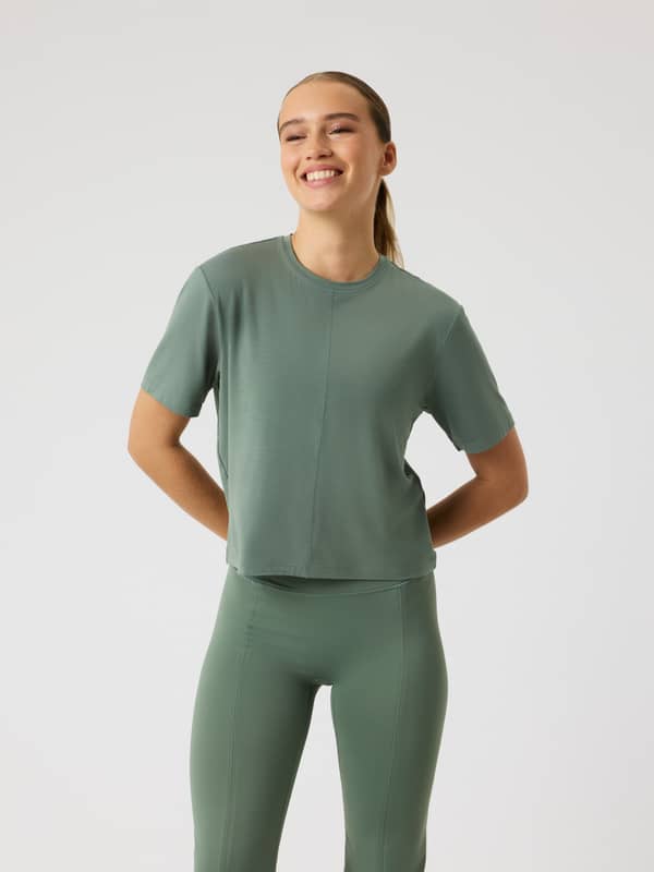 Front view of a model wearing the Studio Soft T-Shirt in Agave Green (Green), a cropped training top for women.