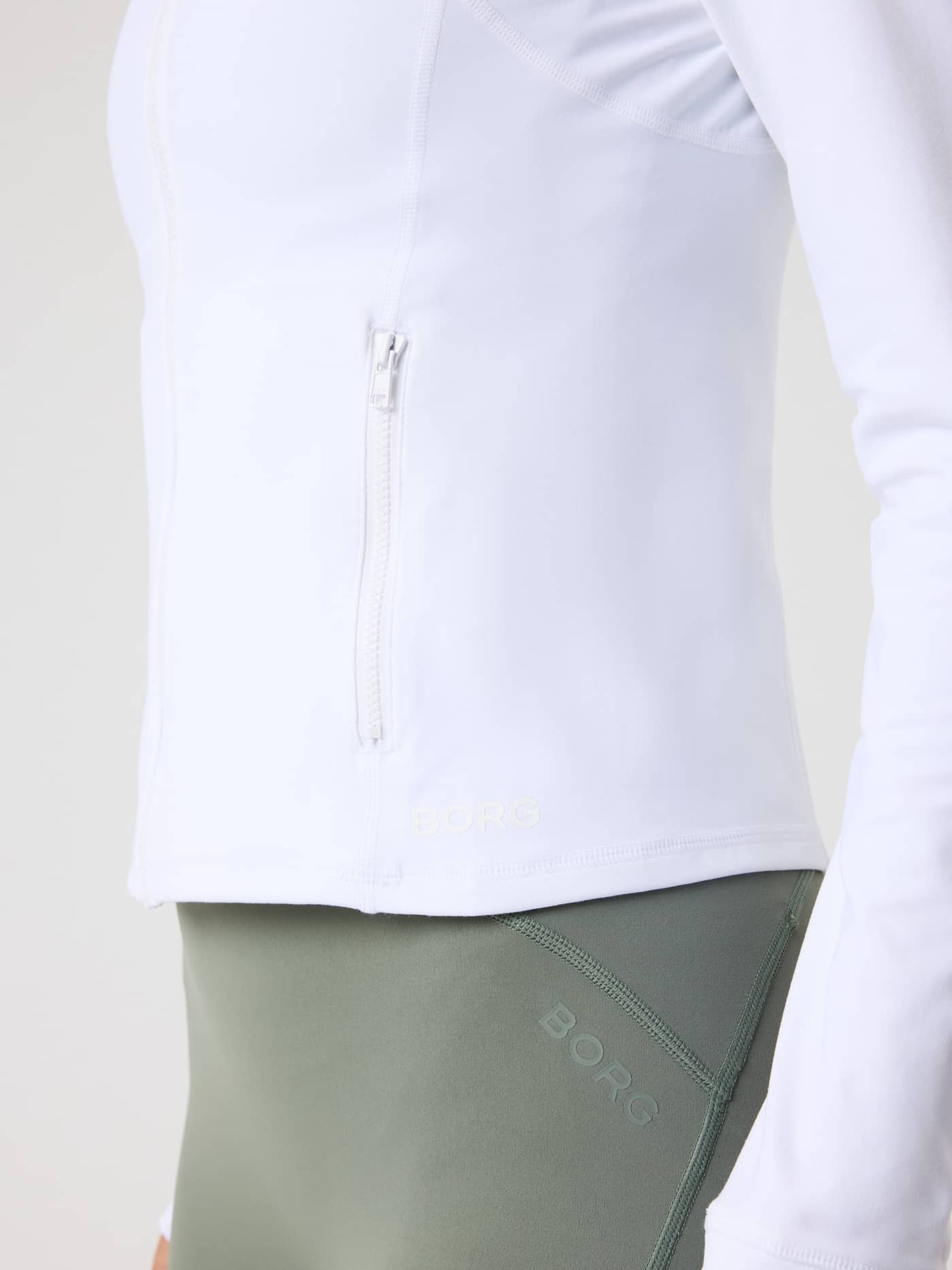 Close-up of the slim fit Björn Borg Soft Zip Midlayer in Brilliant White (White) for training, showing the tonal BORG logo. - Image 7