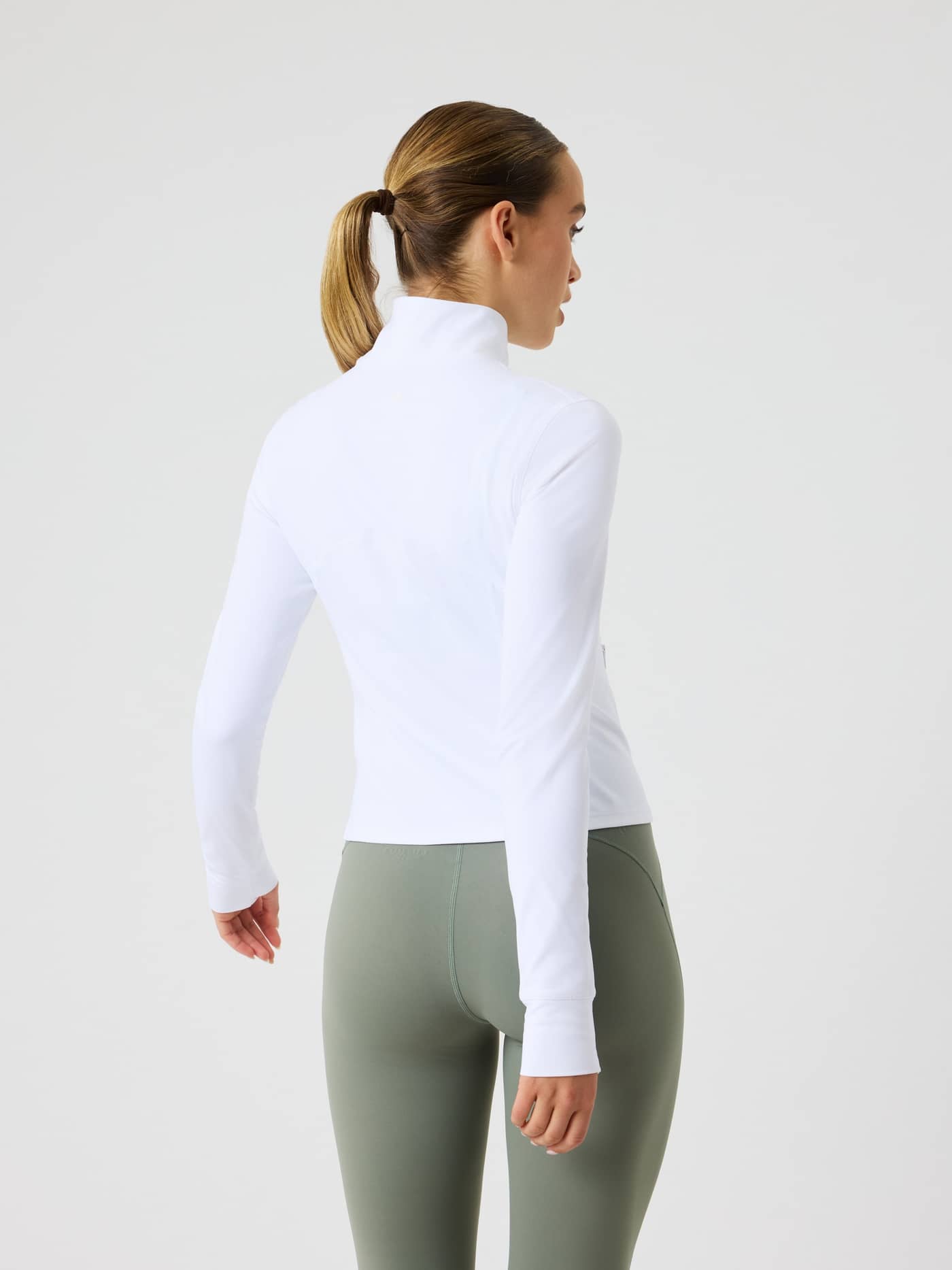 Back view of a woman wearing the slim-fit Borg Soft Zip Midlayer with a mock neck in Brilliant White (White) for training. - Image 4
