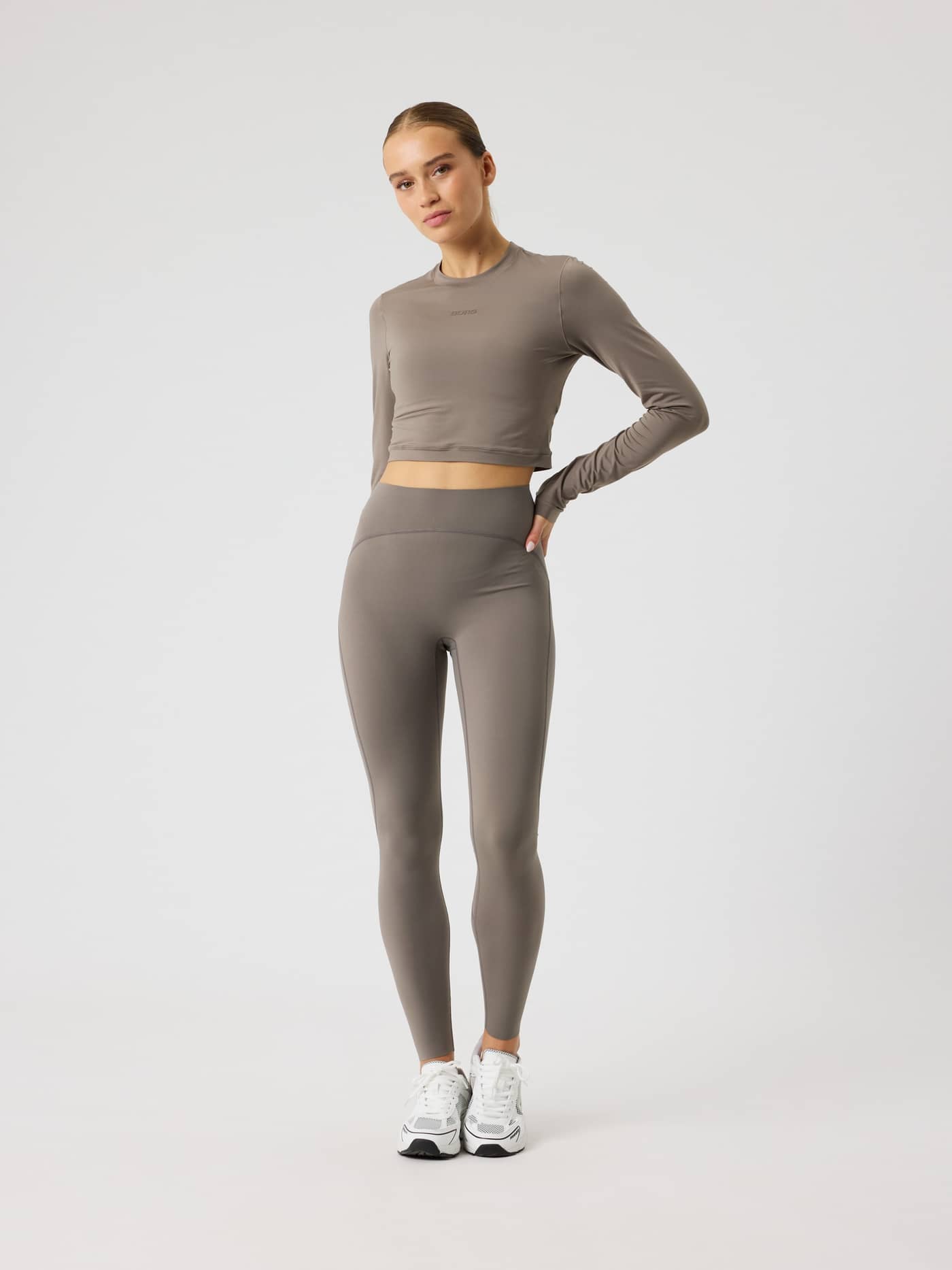 Vue de face d'une femme en Studio Soft Cropped Longsleeve Falcon (Brun) et leggings assortis pour l'entraînement. - Image 3
