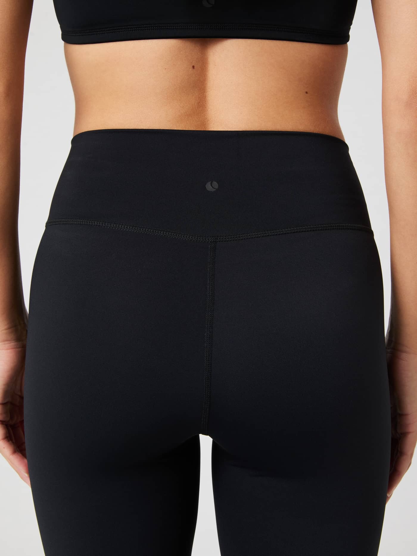 Studio Flared Slit Tights in Black Beauty (Black) from the back, featuring a tonal logo and supportive training fit. - Image 5