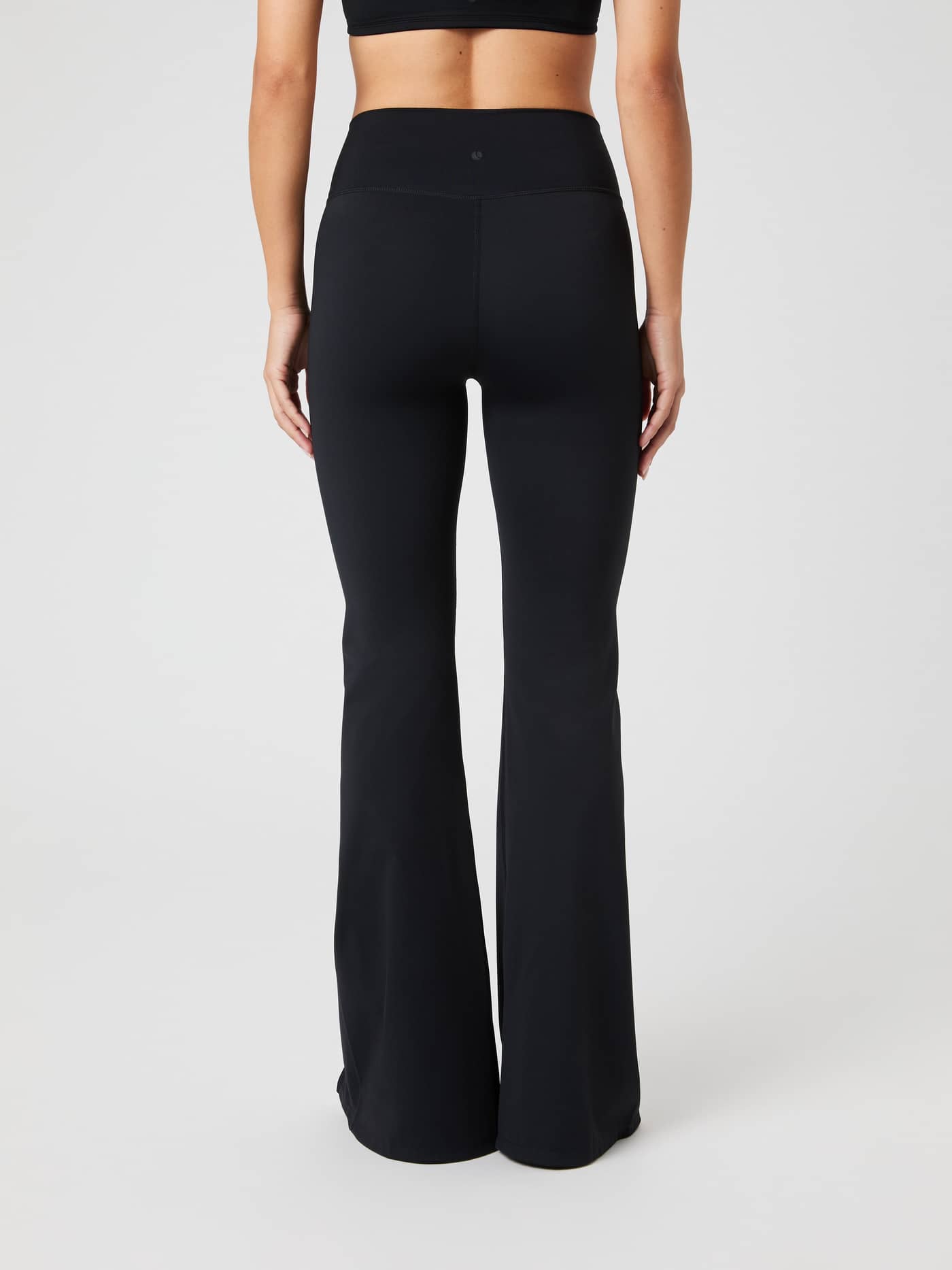 Back view of a model wearing Studio Flared Slit Tights in Black Beauty (Black) with a stylish flared fit for training. - Image 4