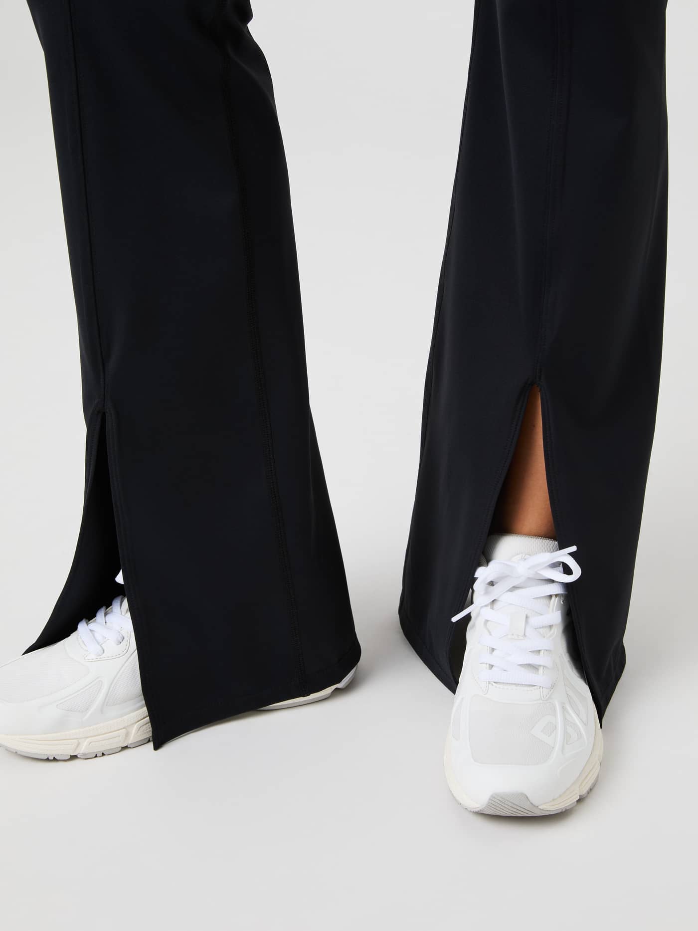 Close-up of the flared leg openings and high slits on the Black Beauty (Black) Studio Flared Slit Tights for training. - Image 6