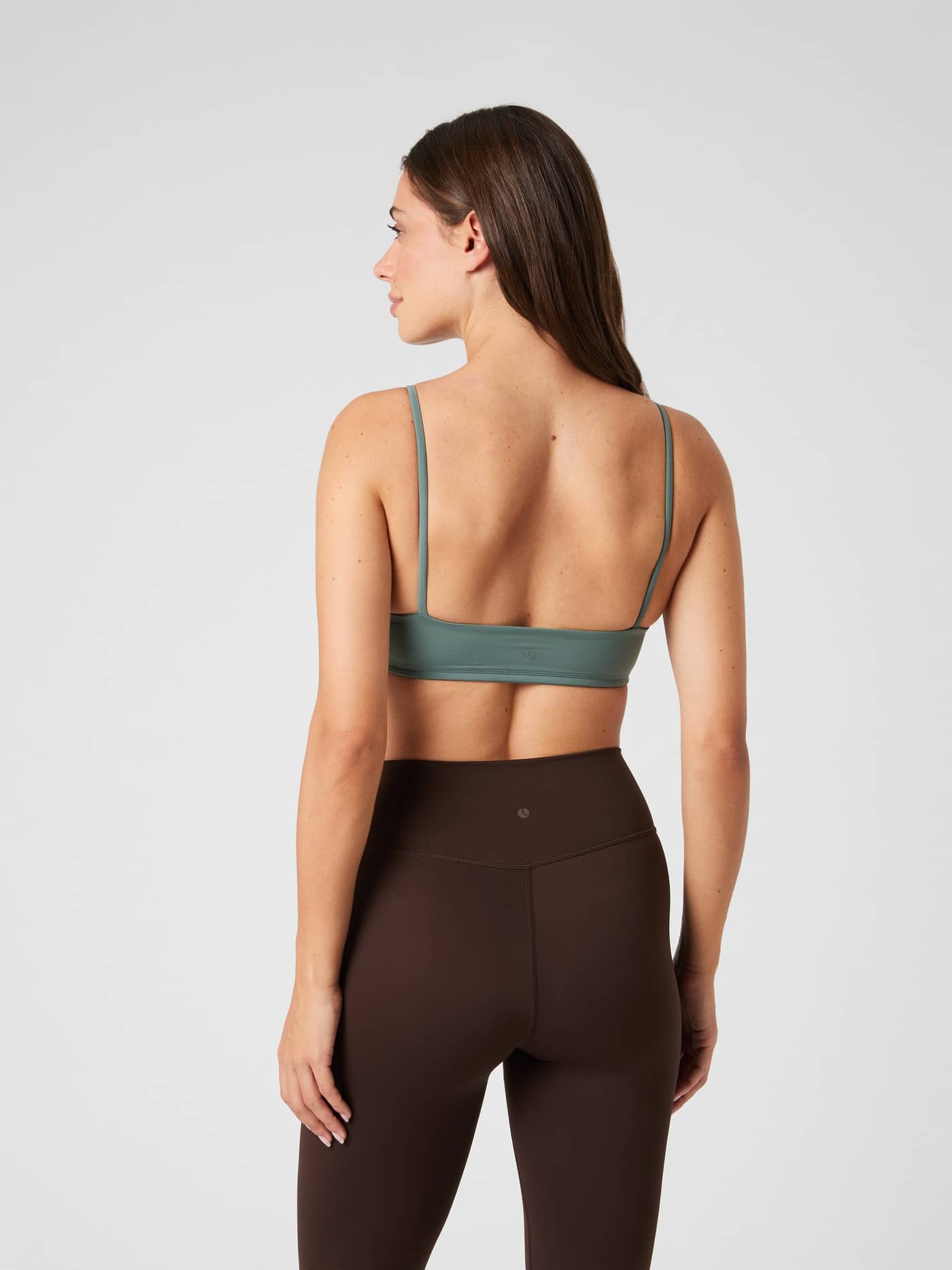Back view of a woman wearing the green Studio Soft Padded Bra, designed for style and a flexible fit during training. - Image 4