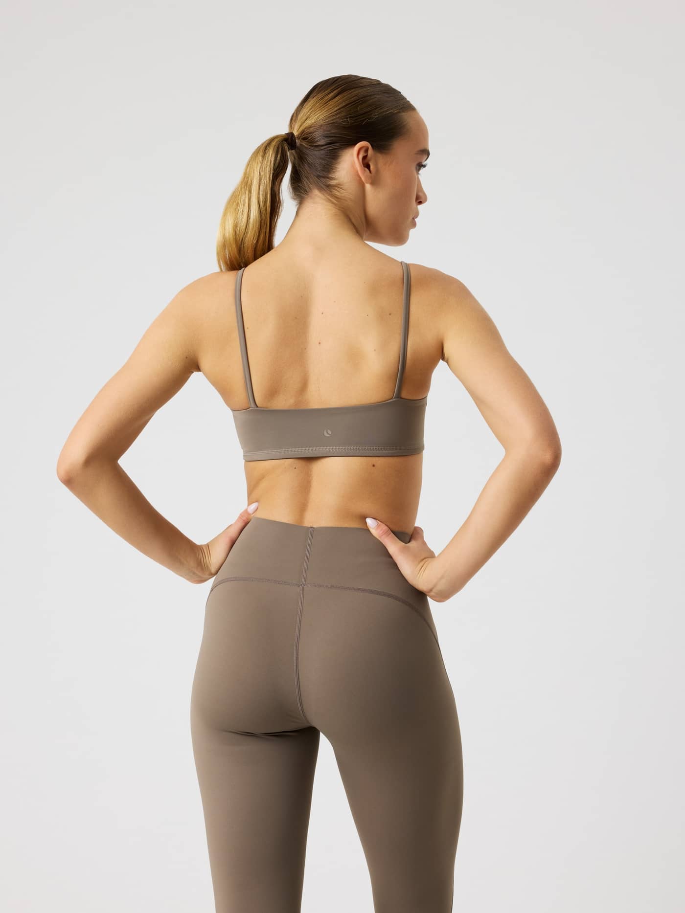 Back view of a model wearing the brown Björn Borg Studio Soft Padded Bra, offering a stylish fit for training. - Image 2