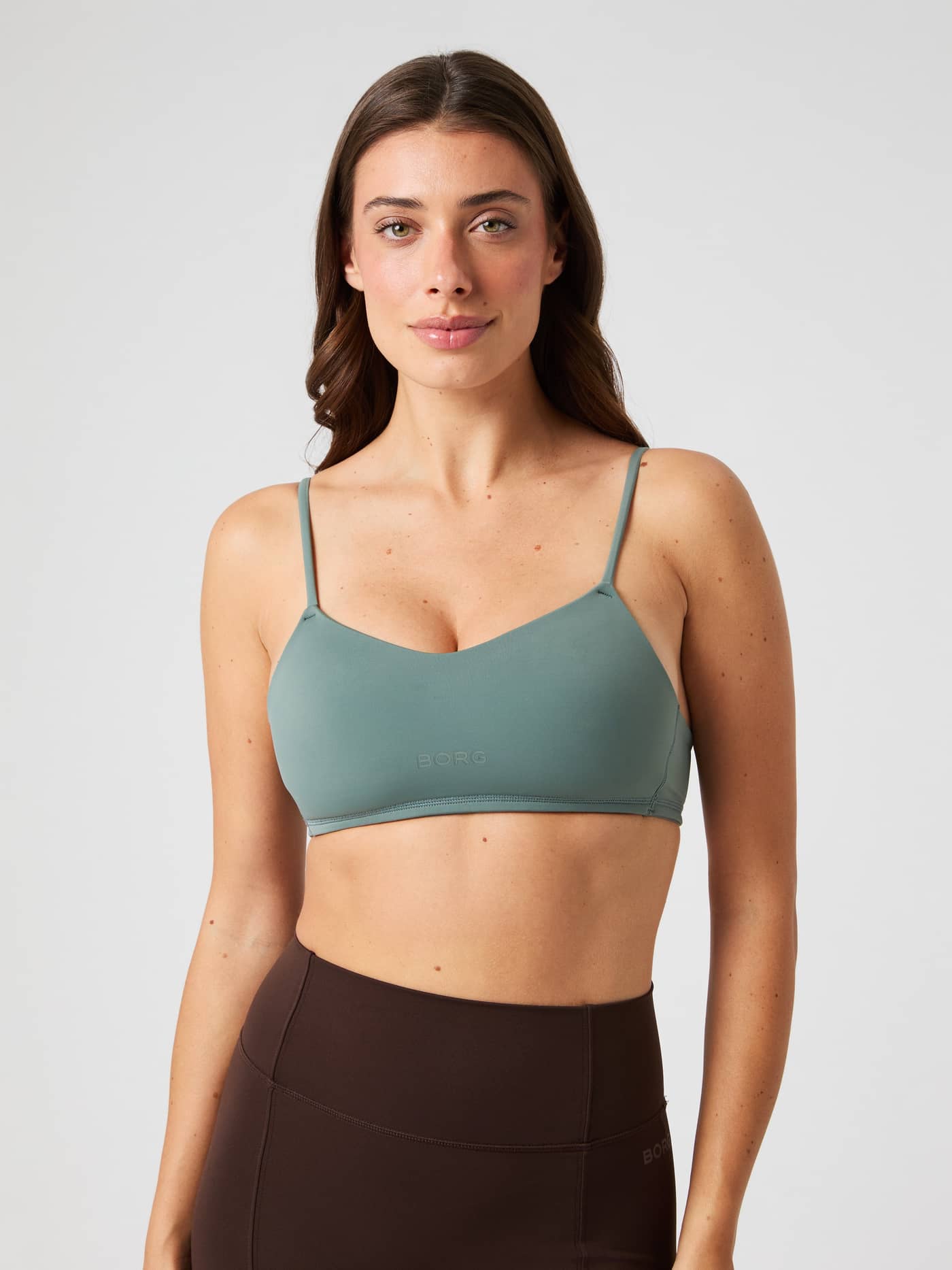 Front view of a model wearing the Björn Borg Studio Soft Padded Bra in Green, providing a stylish fit for training. - Image 1