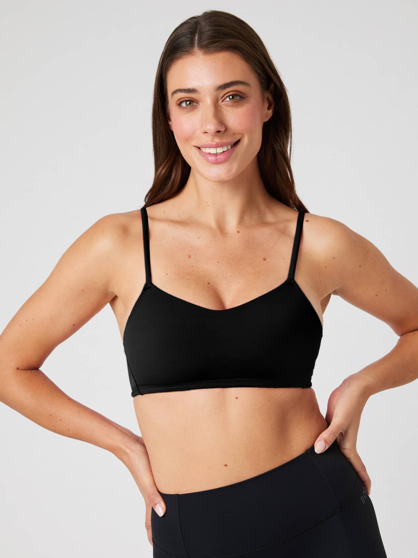 Front view of a woman wearing the black Studio Soft Padded Bra, a supportive training top with a tonal BORG logo. - Image 5