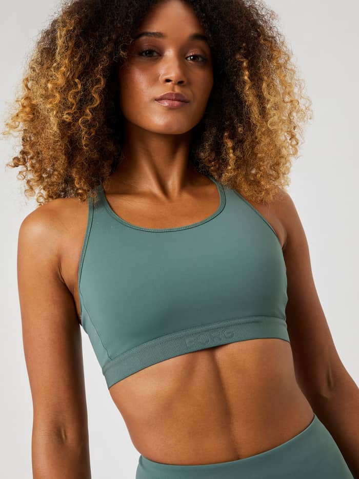 Modell framifrån i Borg Low Support Sports Bra i Balsam Green (Grön) för träning med en grön präglad logotyp. - Image 3
