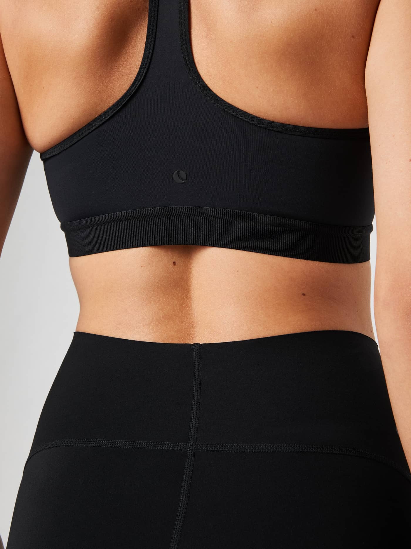 Vue de dos d'un mannequin portant le Borg Low Support Sports Bra noir pour l'entraînement, avec logo en relief ton sur ton. - Image 2