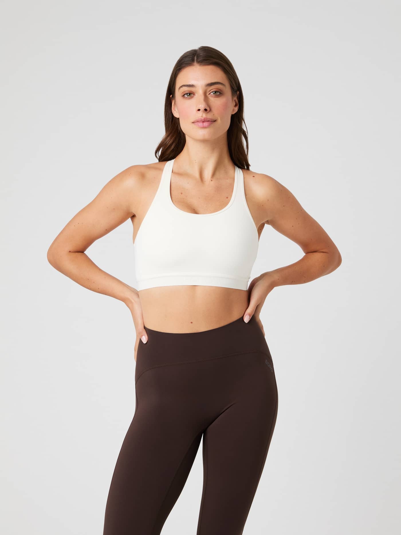 Front view of a model wearing the Borg Low Support Sports Bra in Tofu (White), designed for a stylish training fit. - Image 1